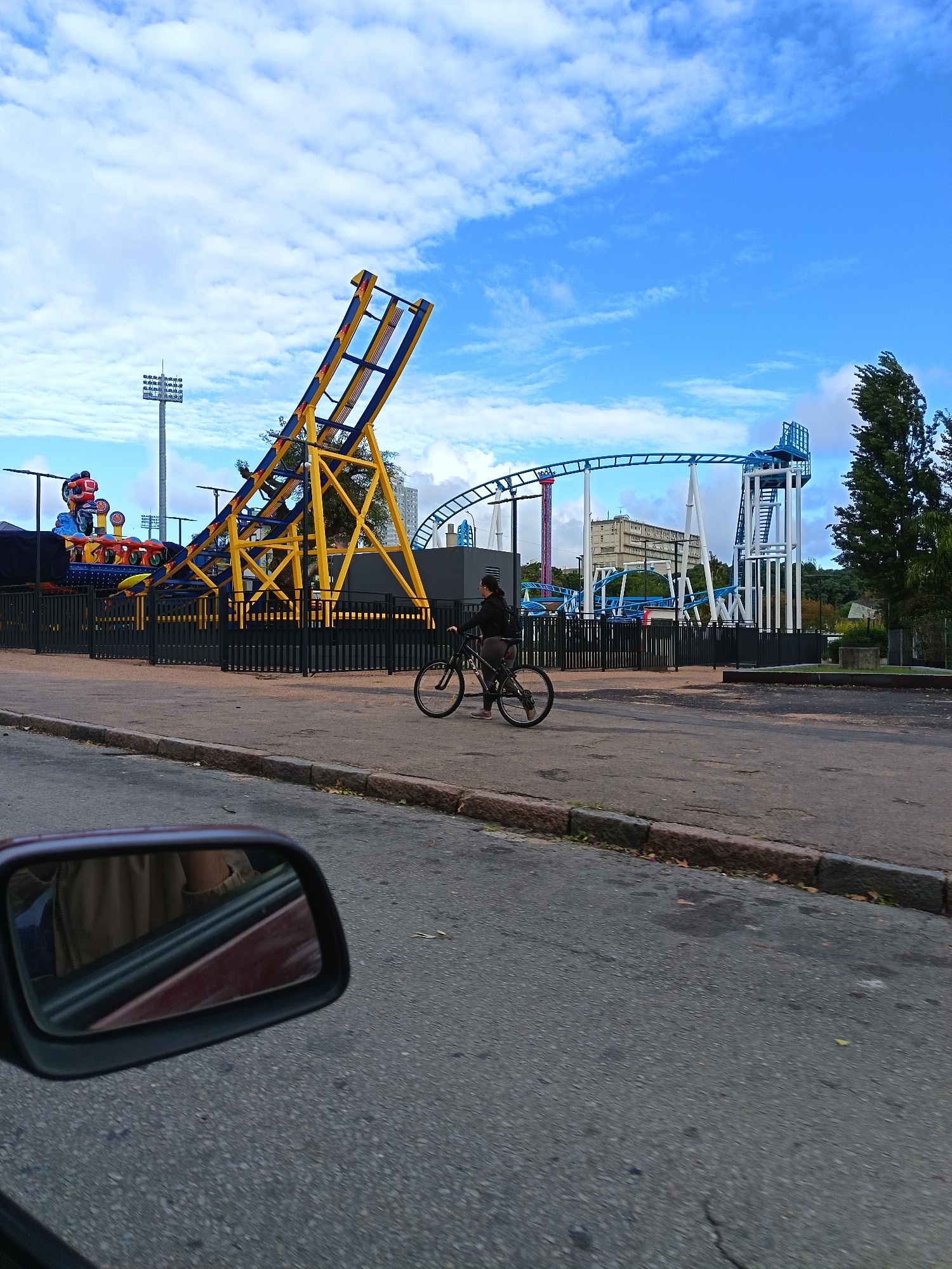 Woman cycles past amusement park rides in Montevideo street