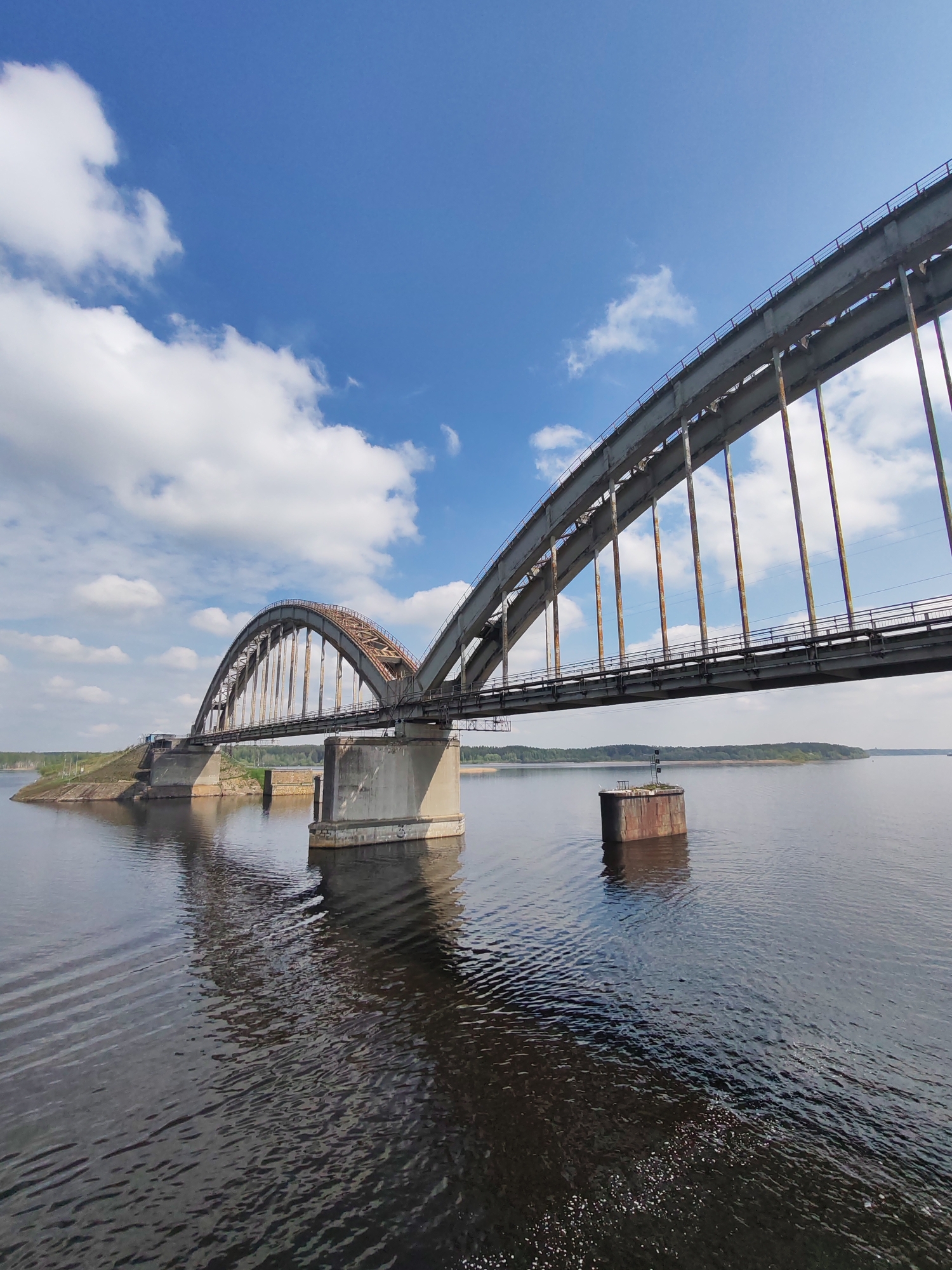 Bridge spanning river observed from land and water in Gladyshevo