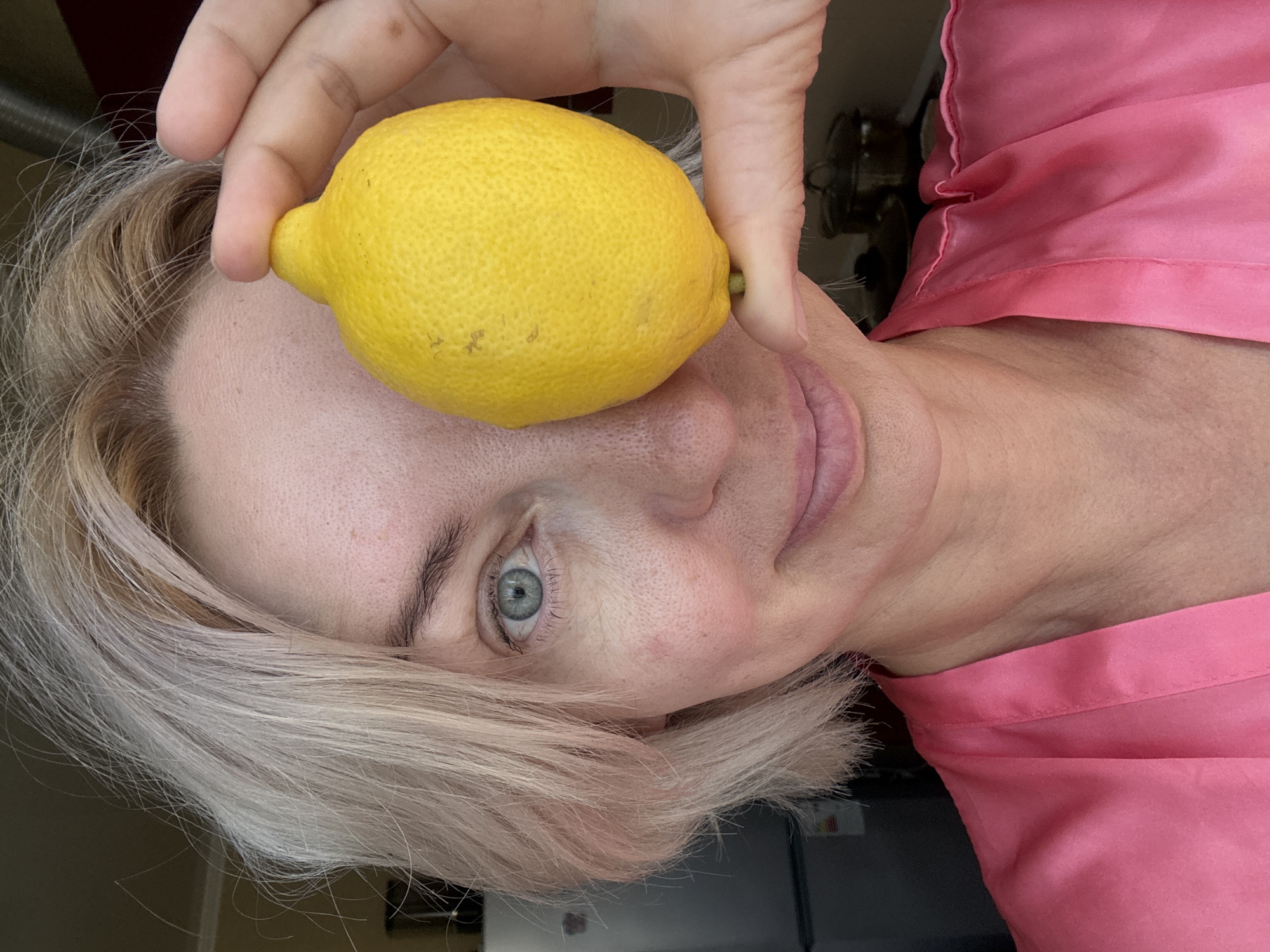Lemon held to eye, pink robe, direct camera gaze in Sochi
