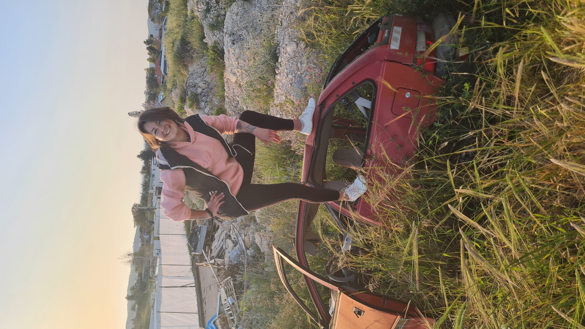 Woman poses on car wreck in Israeli countryside