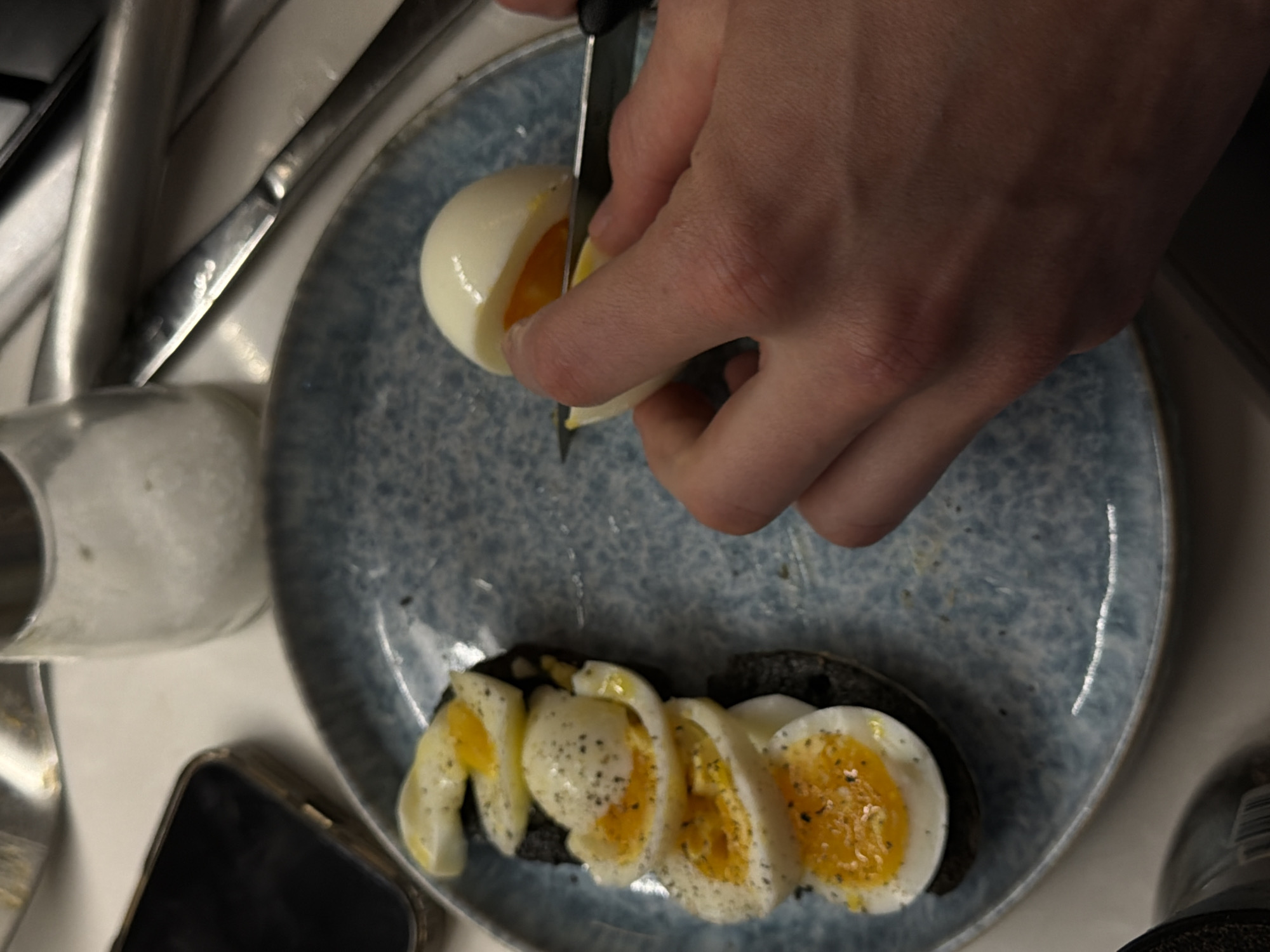 Person prepares food, slices boiled egg in London kitchen