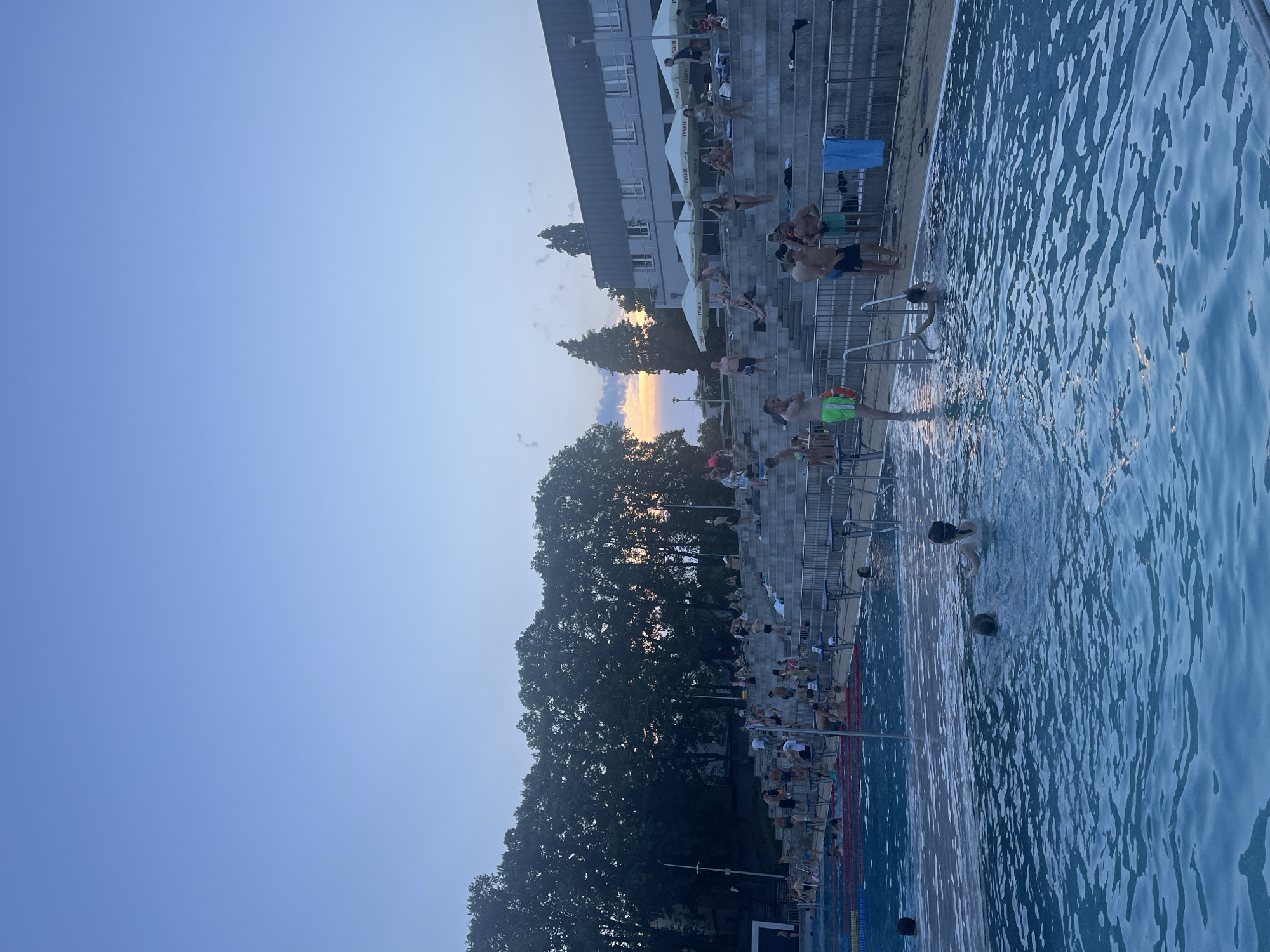 Crowded outdoor pool at golden hour, lanes full