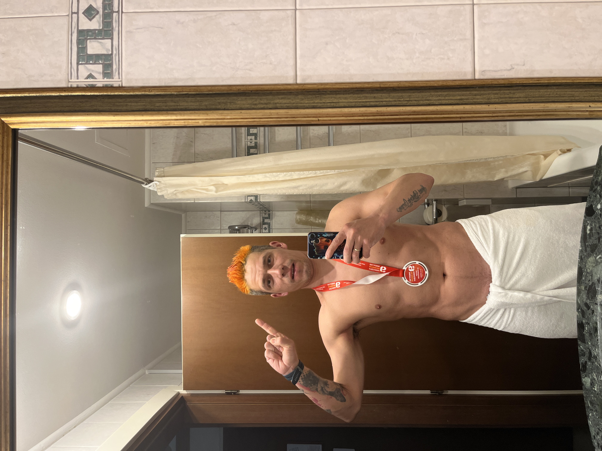 Orange-haired man takes towel selfie with medal in Moscow bathroom