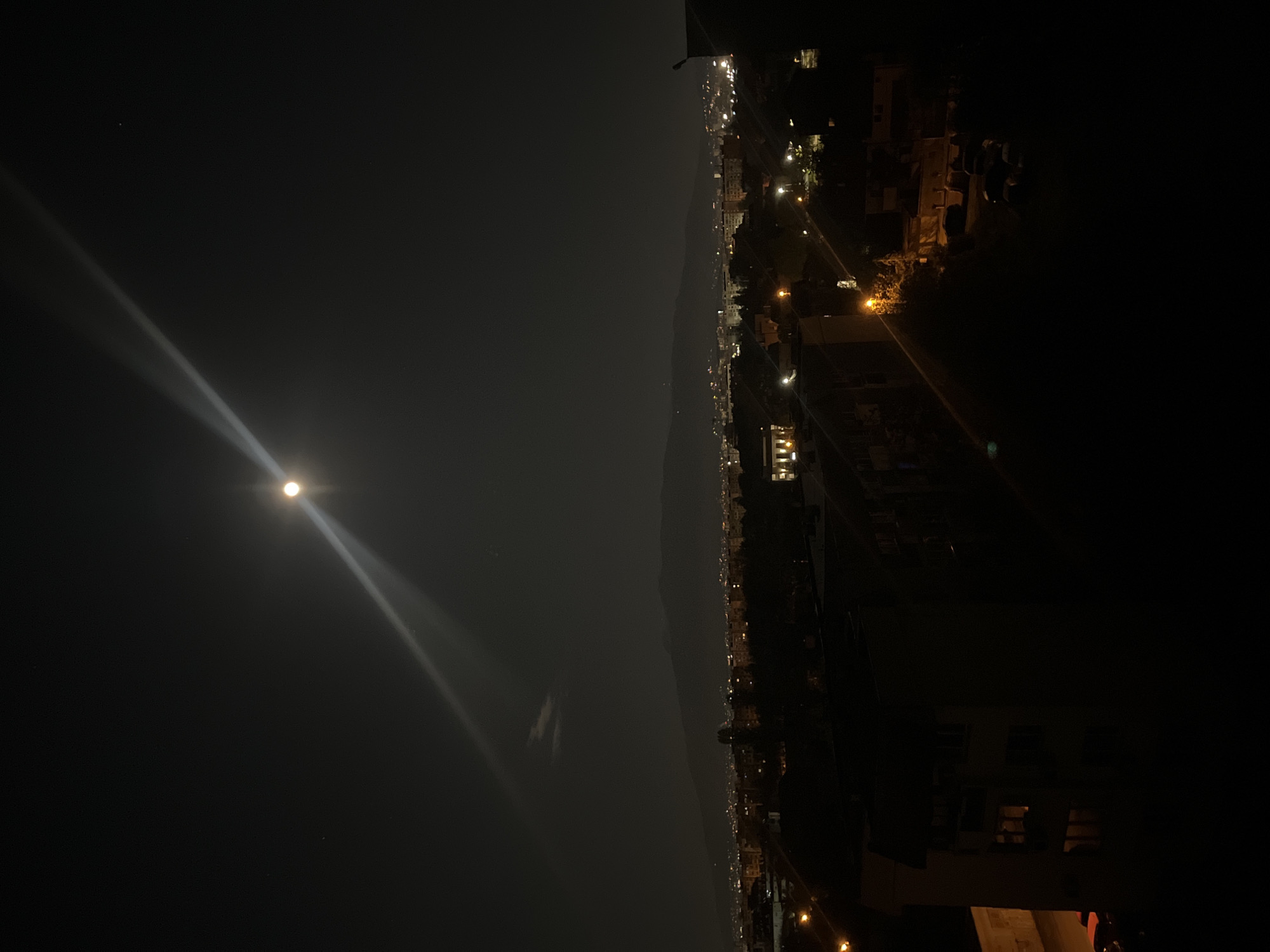 Bright moon with light beams observed over Sofia cityscape