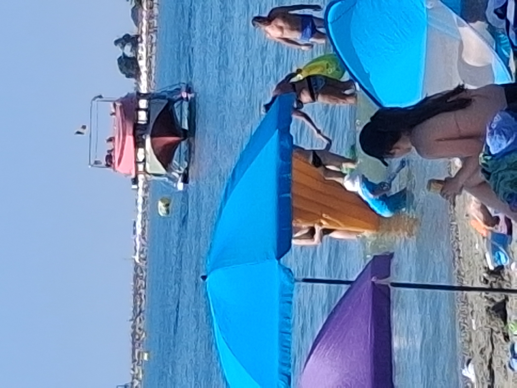 Crowded sunny beach with colorful umbrellas packed shoreside