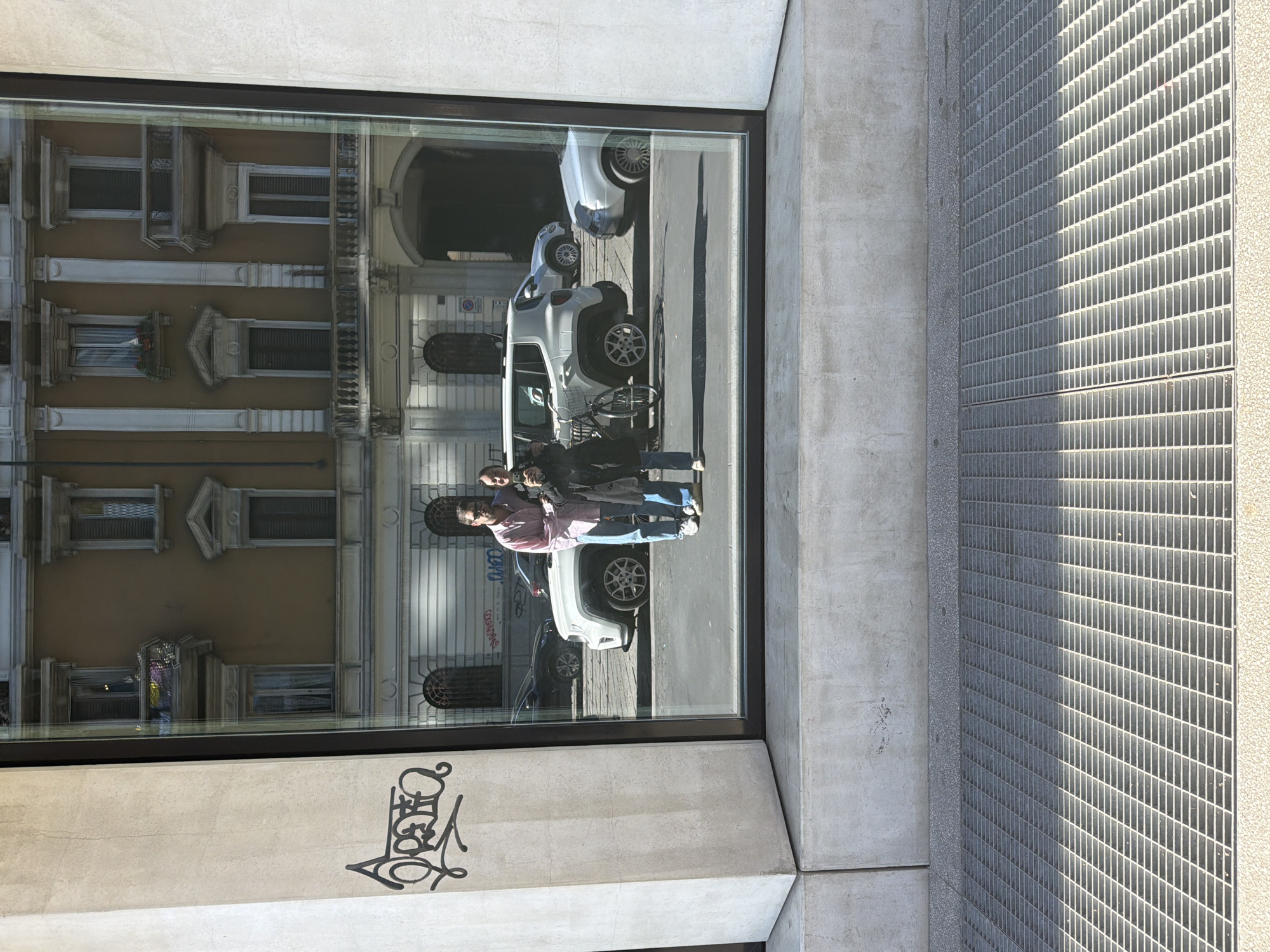 Reflective building window mirrors street scene in Milan