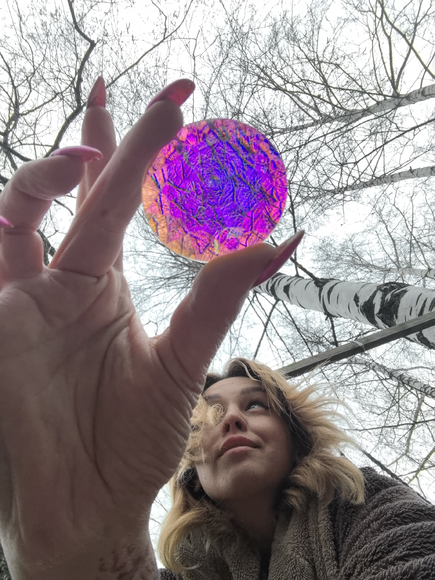 Woman holds iridescent disc creating rainbow effects in Noviy