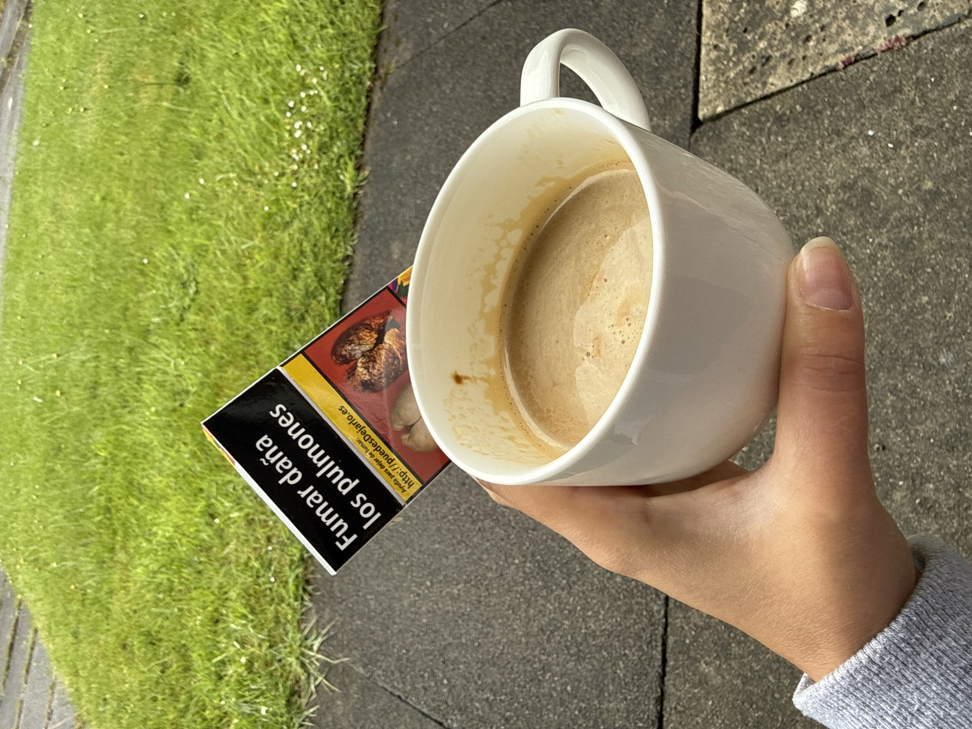 Coffee break moment captured over cigarette packet on pavement