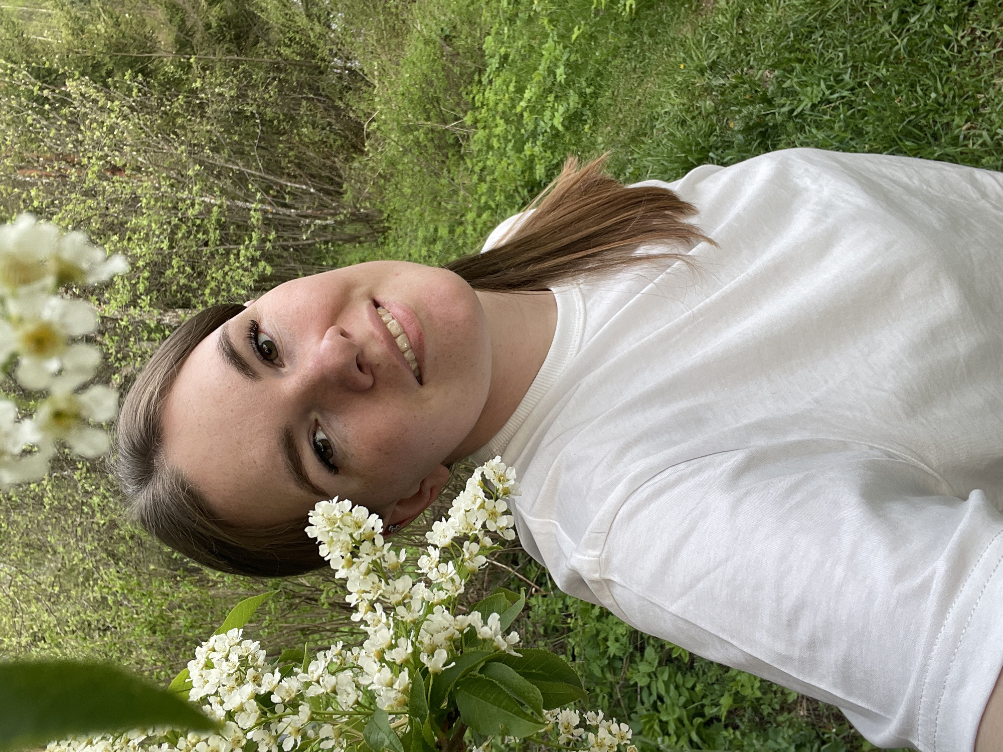 Woman poses for outdoor photo session amid flowers in Zhigalki