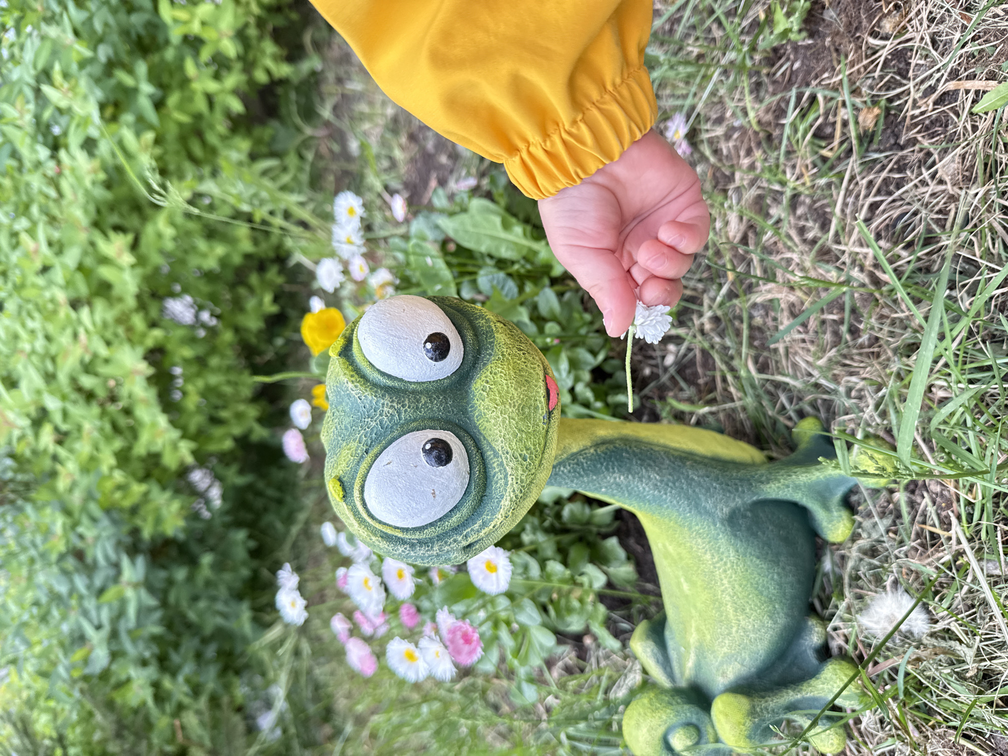 Child with flower plays near frog garden ornament in Moscow