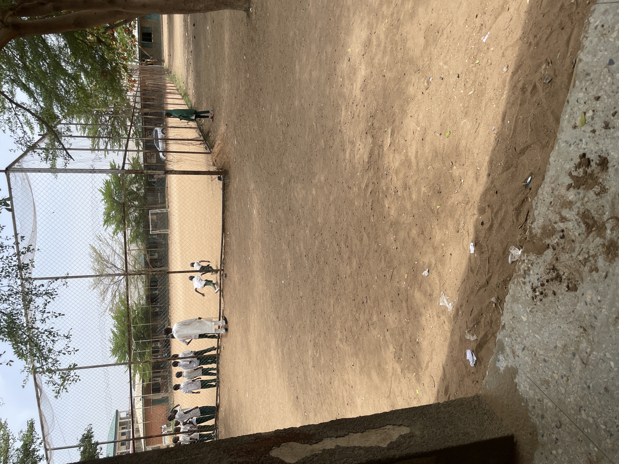 Youth play soccer on dirt field in Nigeria