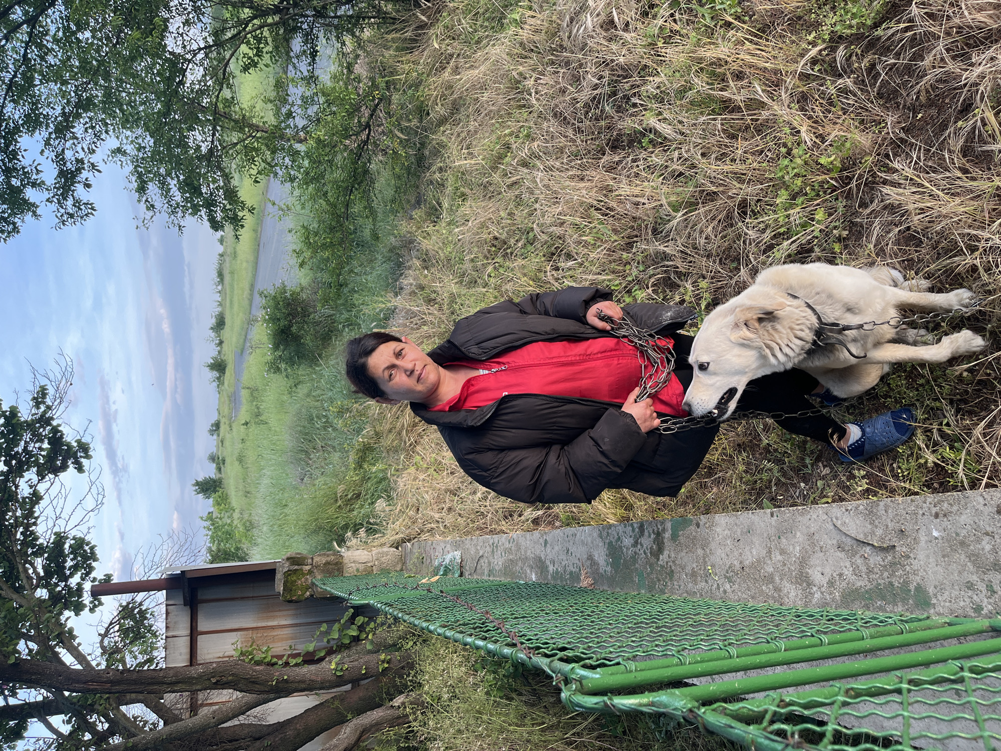 Woman sits with chained dog in rural Bulgarian village