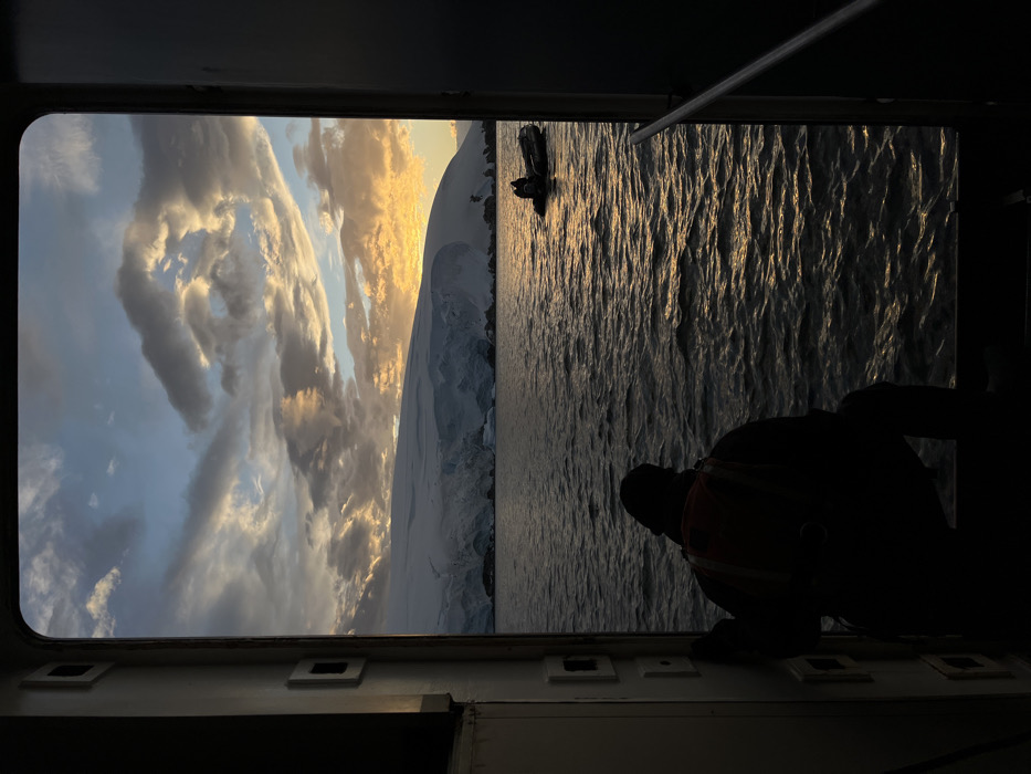 Golden sunset illuminates dramatic clouds over Antarctic mountains