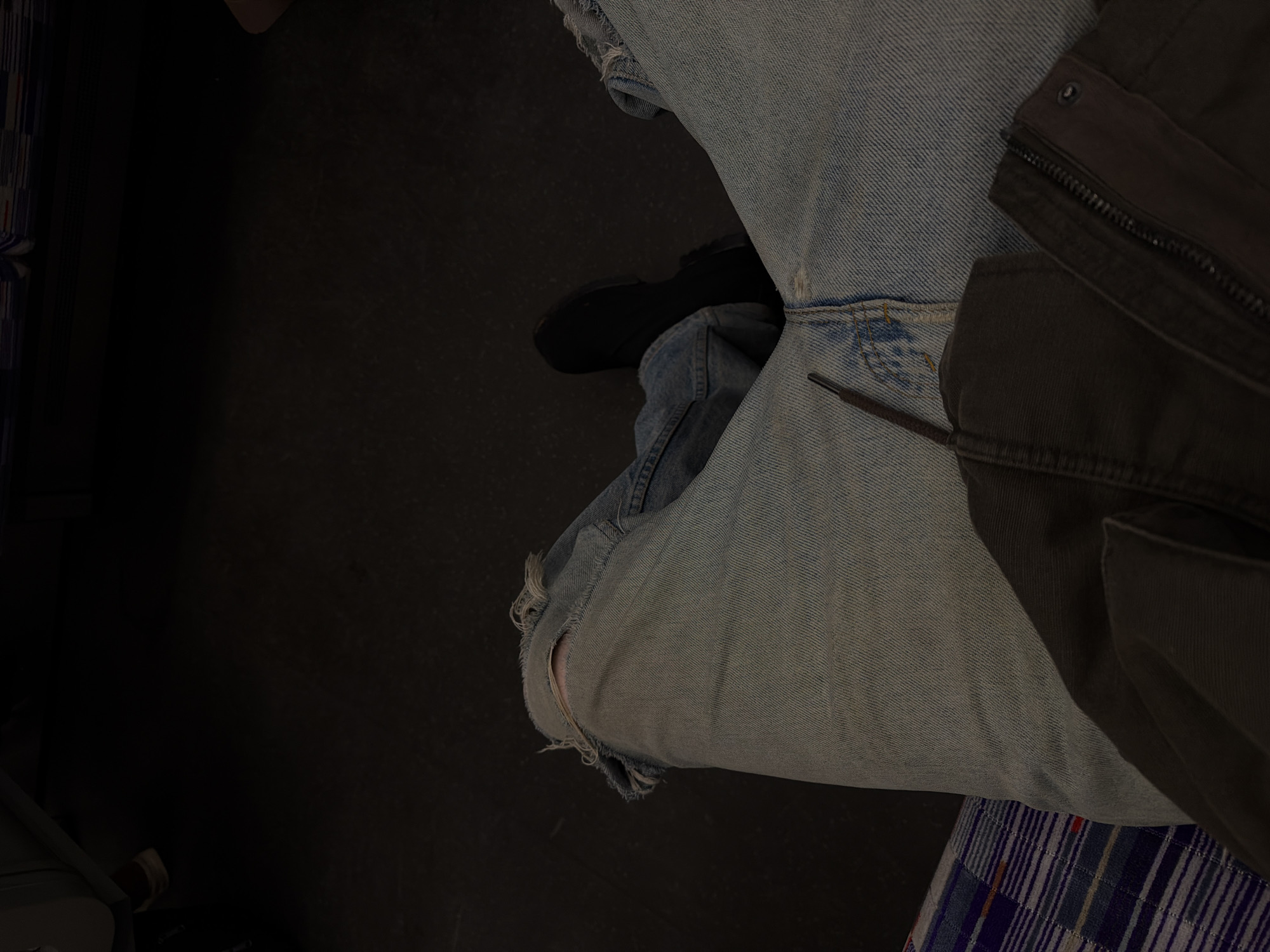 Person in ripped jeans observed seated indoors in London