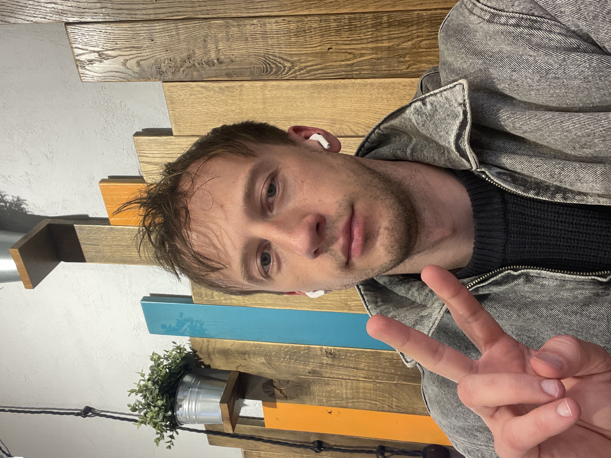 Man takes indoor selfie wearing earbuds in Murino