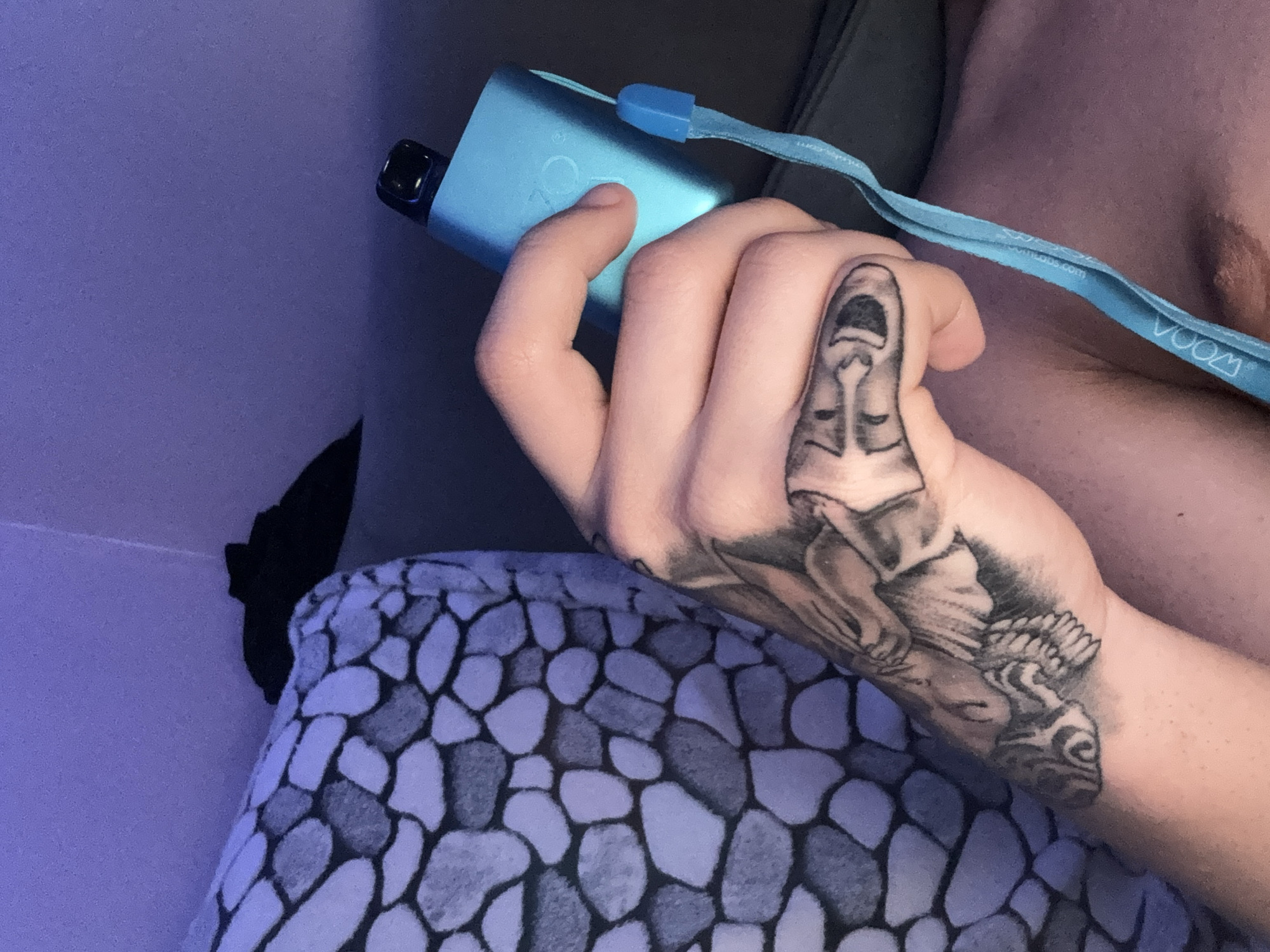 Person with tattoos photographed indoors making peace sign gesture
