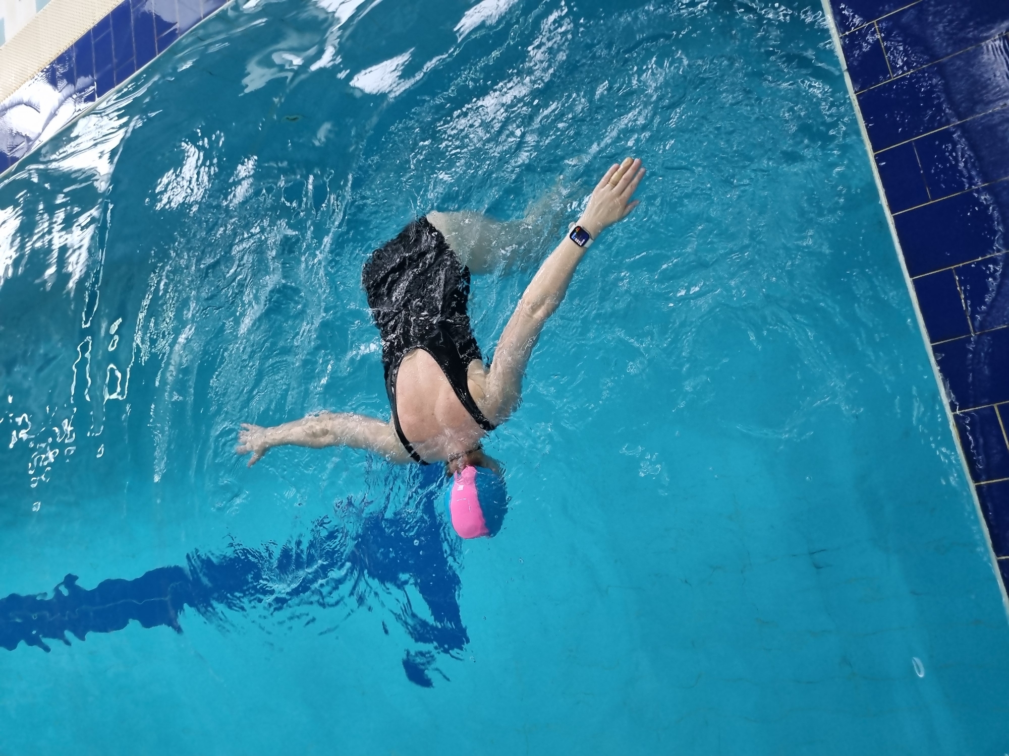 Swimmer performs breaststroke in pool during early morning hours