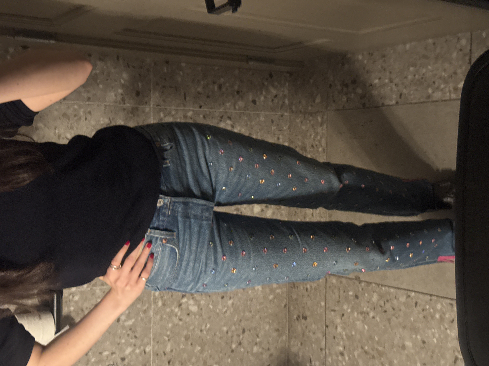 Person in embellished jeans rests on terrazzo floor in NYC