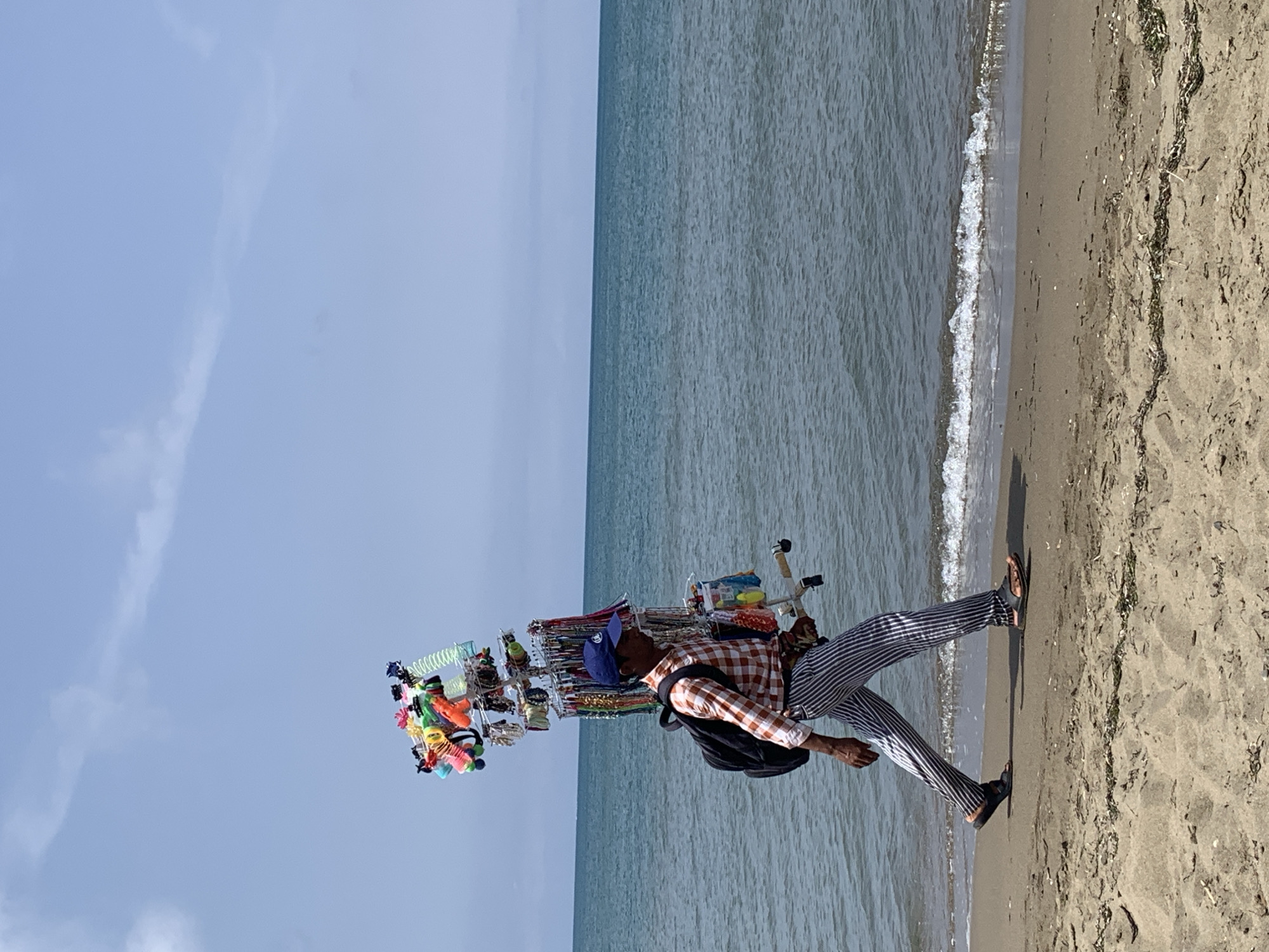 Beach vendor and morning strollers along Orbetello's shoreline