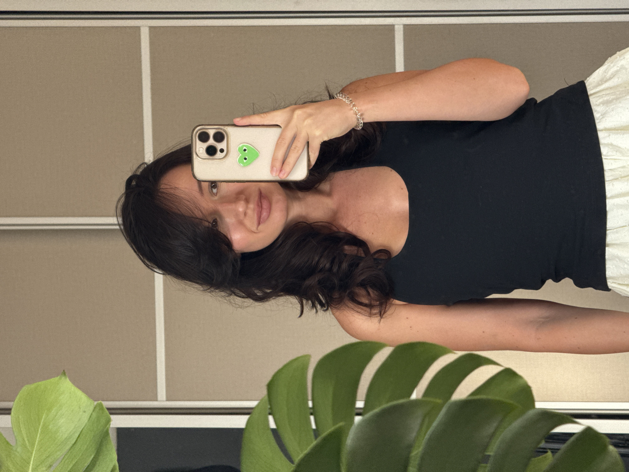 Mirror selfie in a Tel Aviv apartment with monstera backdrop.