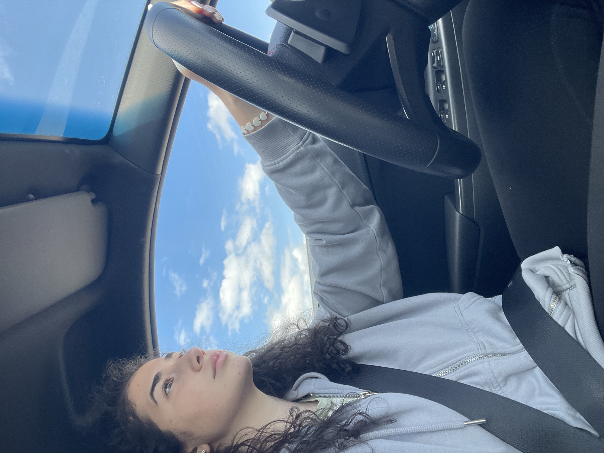 Woman gazes through sunroof while seated in car, Sofia