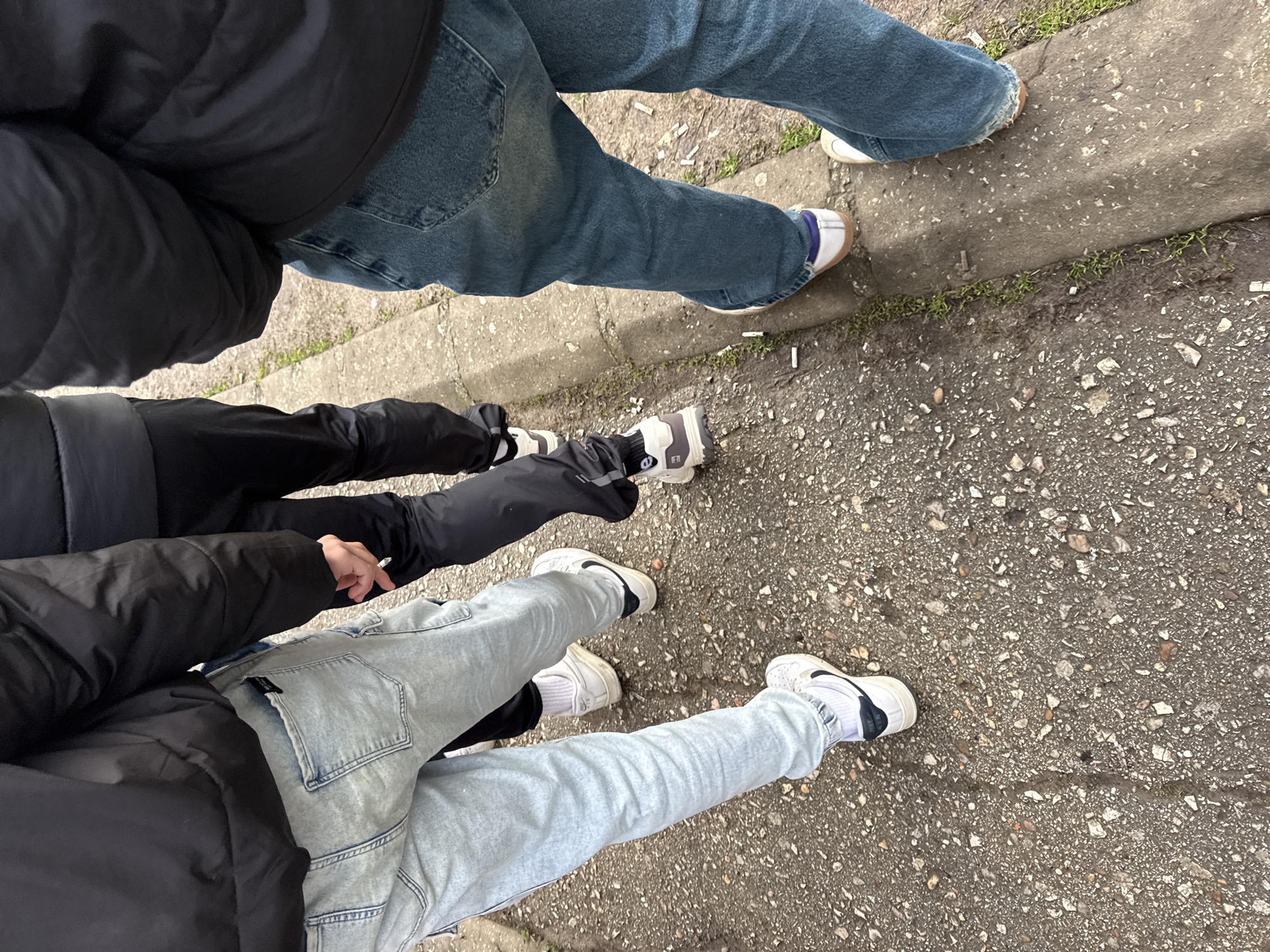 Three people gather on cigarette-strewn sidewalk in Troyan