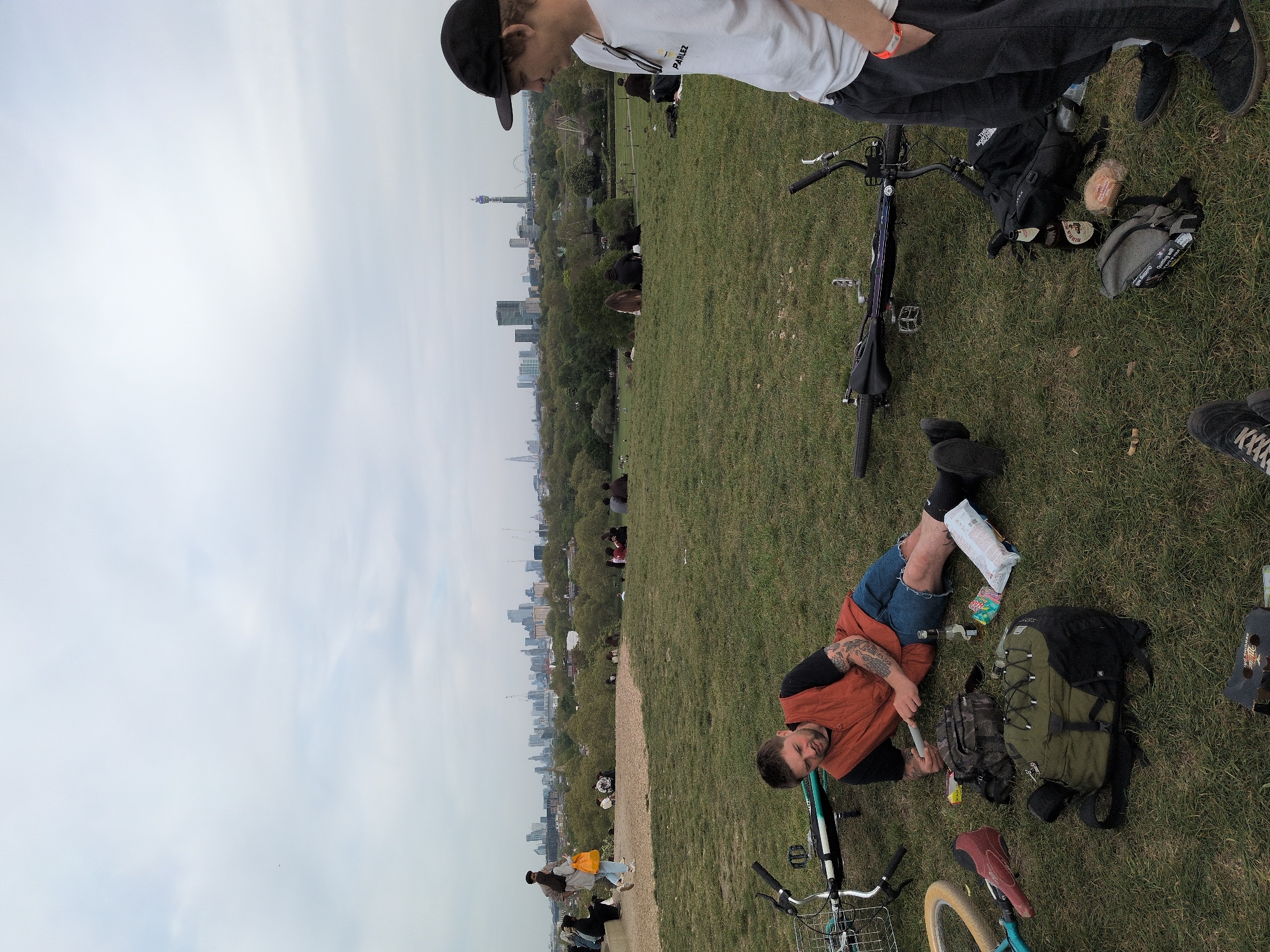 People gather on London hillside park overlooking city skyline