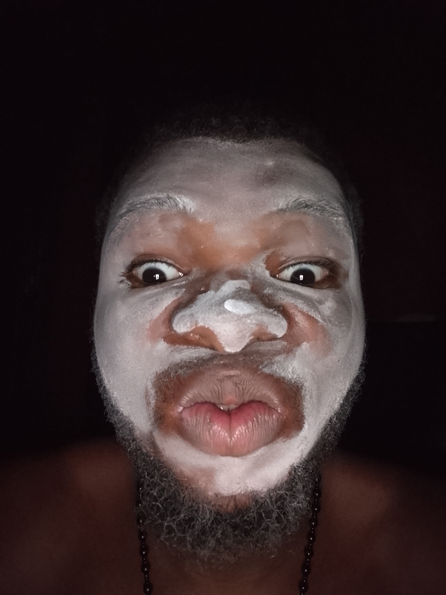 Person photographed in white theatrical face paint during evening hours
