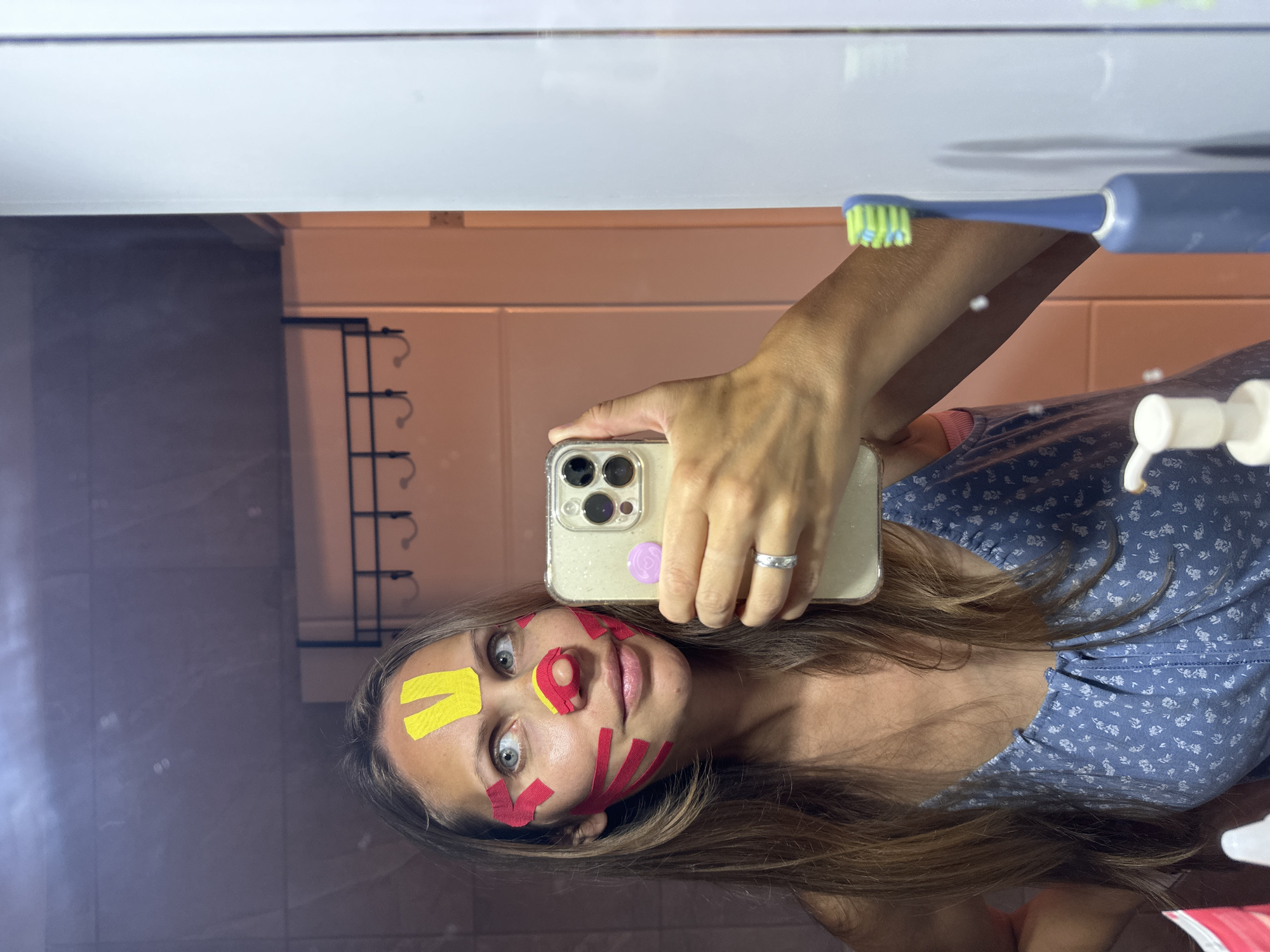 Woman applies colorful tape to face in Turkish bathroom