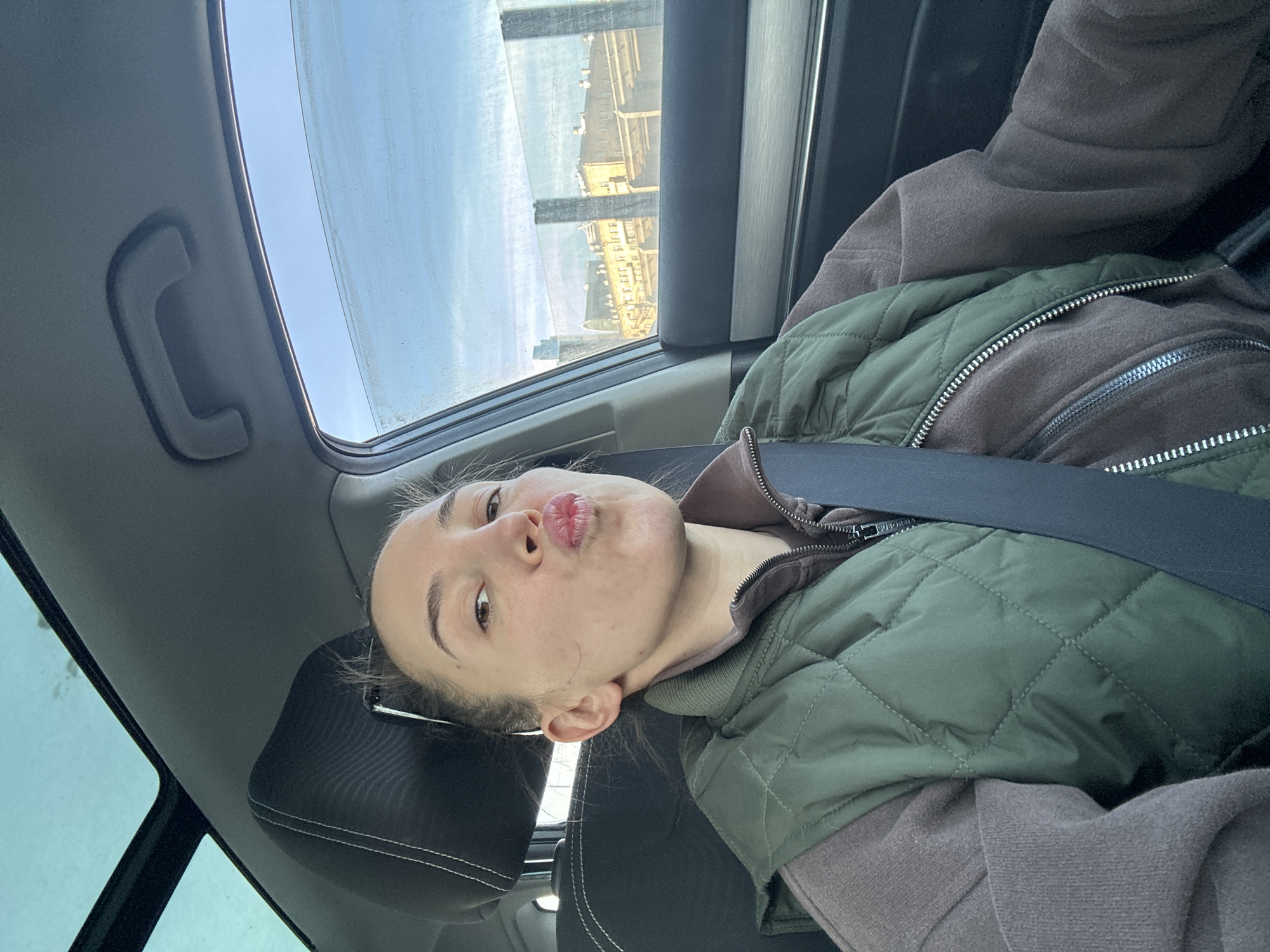 Young woman poses playfully in car passenger seat, Moscow