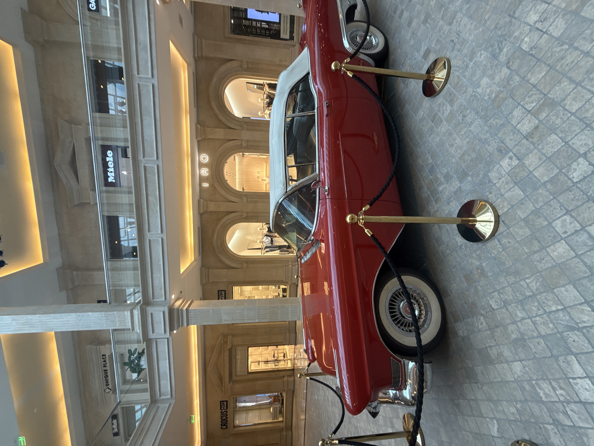 Vintage red Cadillac on display inside a grand indoor atrium