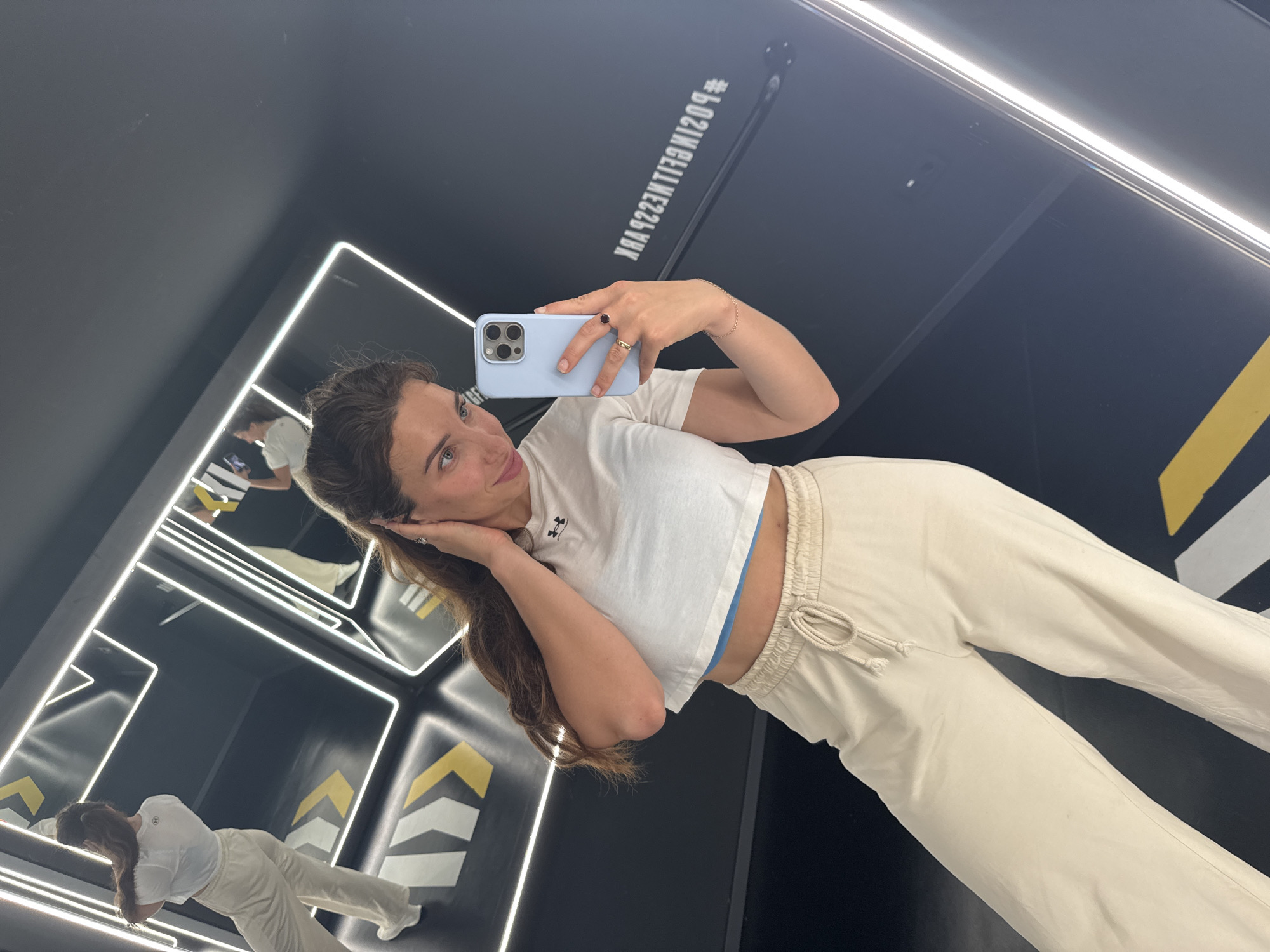 Woman takes selfies in neon-lit mirrored space in Valencia