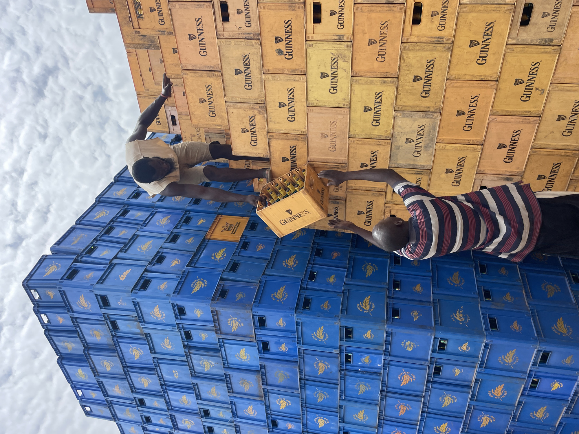 Men gather around beer crate stacks in Bukuru, Nigeria