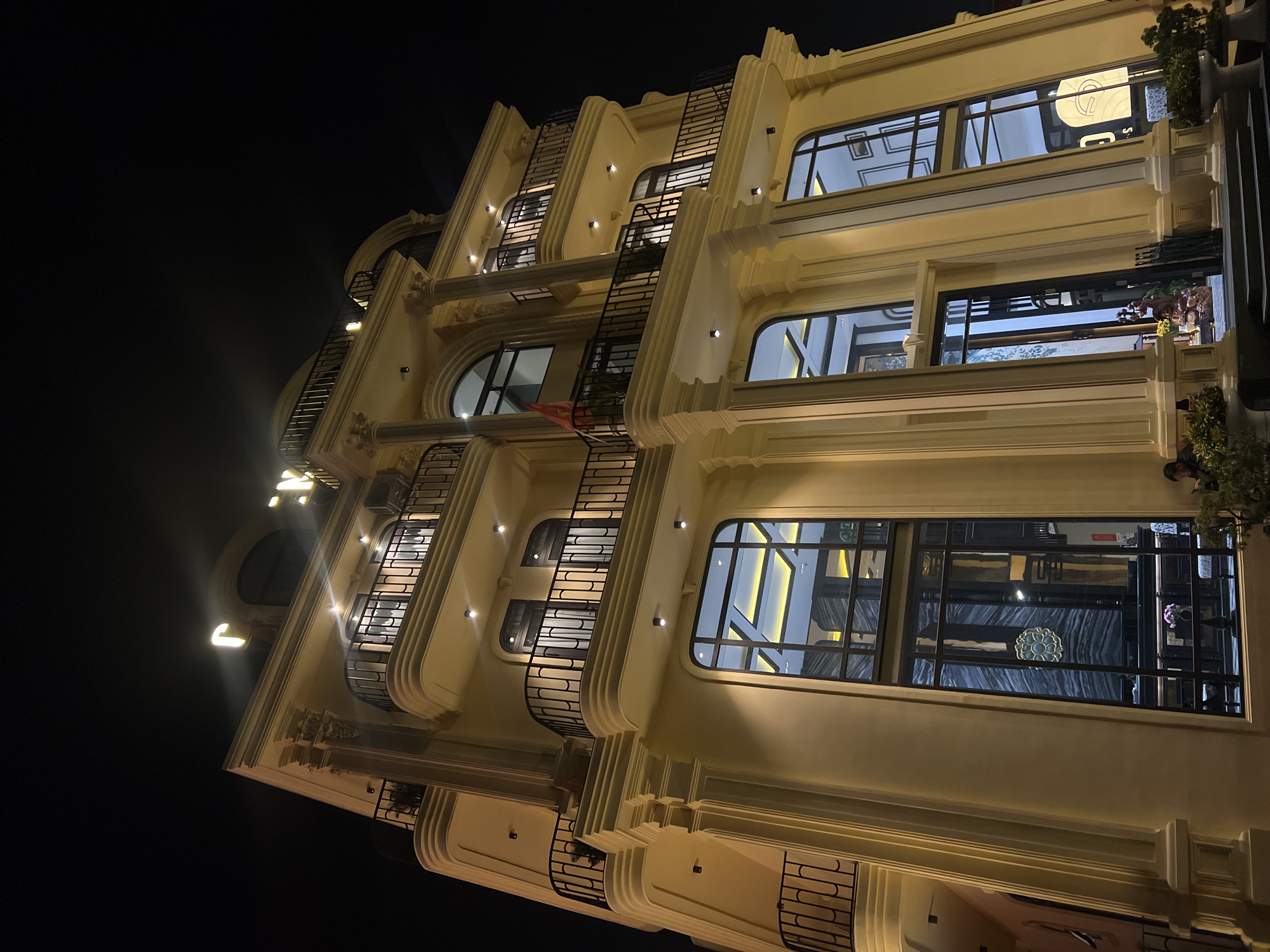 Illuminated yellow building photographed at night in Da Lat