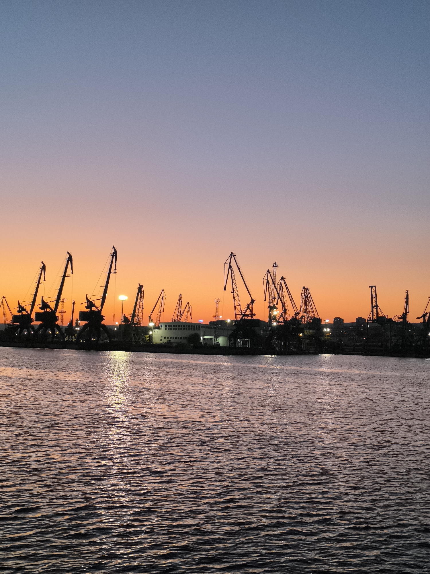 Varna port at dusk and nightfall, ships and city lights on water