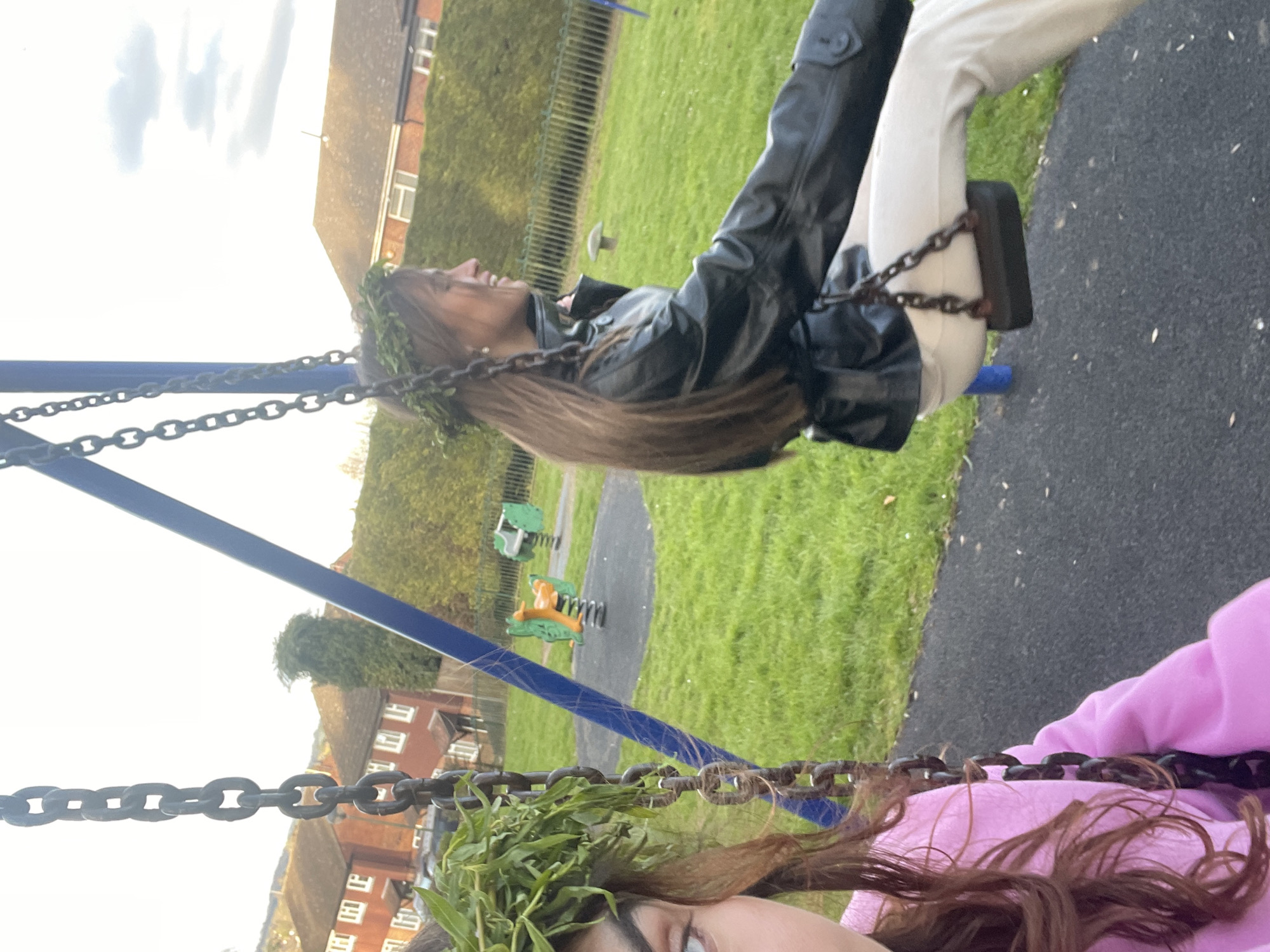 Two people enjoy swings at Maidstone playground on sunny afternoon