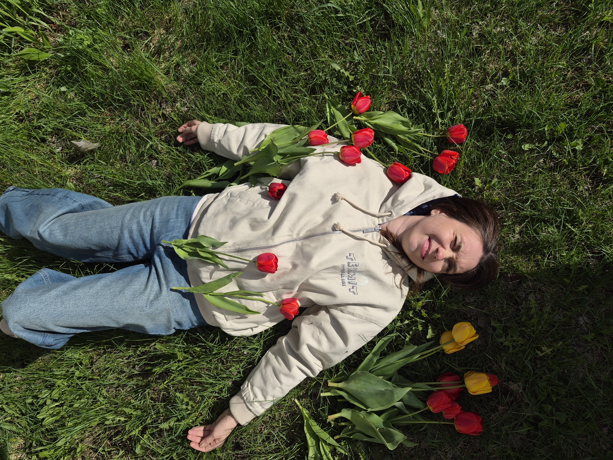 Woman poses with tulips in grass in Chaikovsky