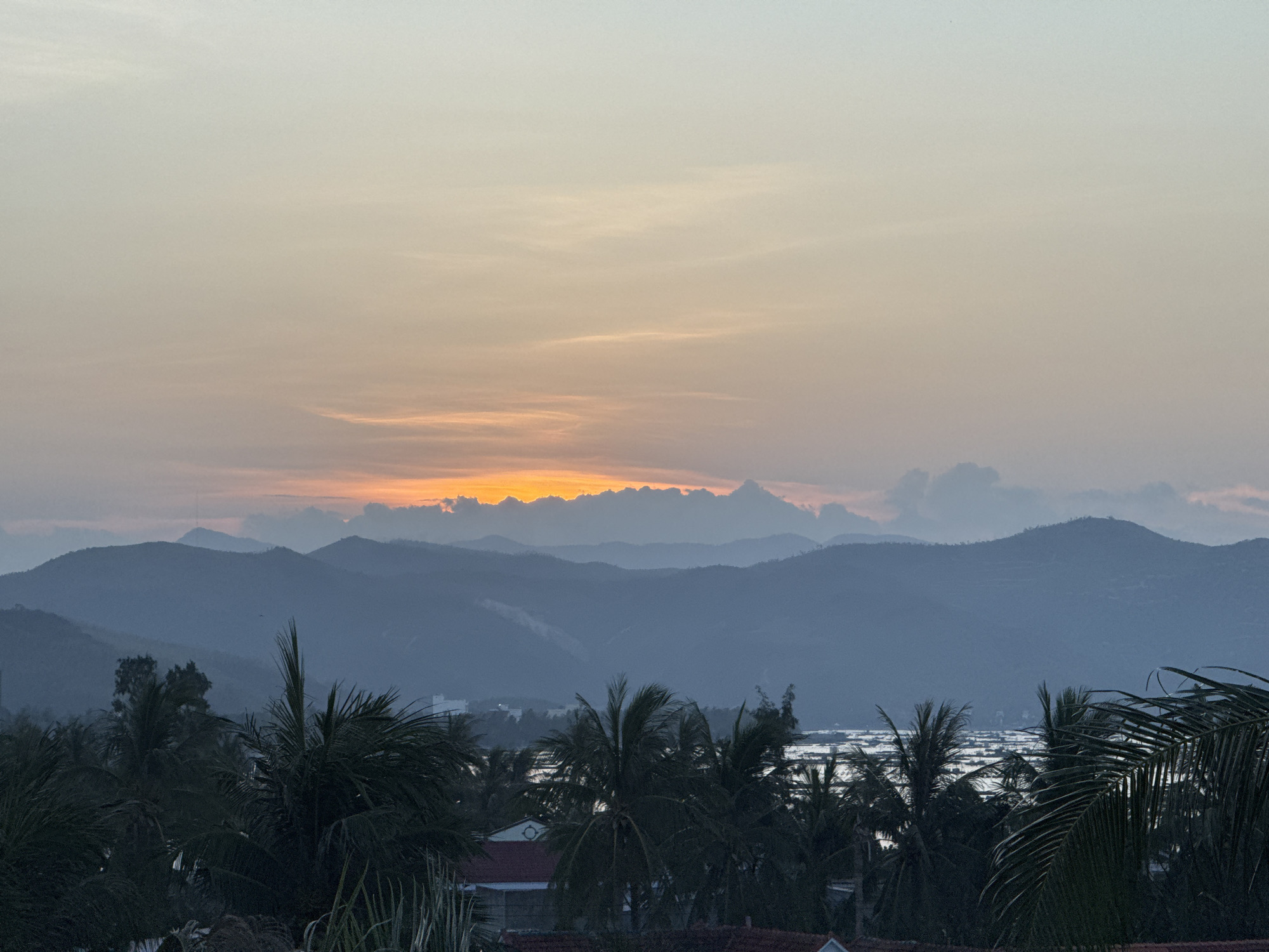 Sunset over Song Cau's coastline, palms and mountains in silhouette