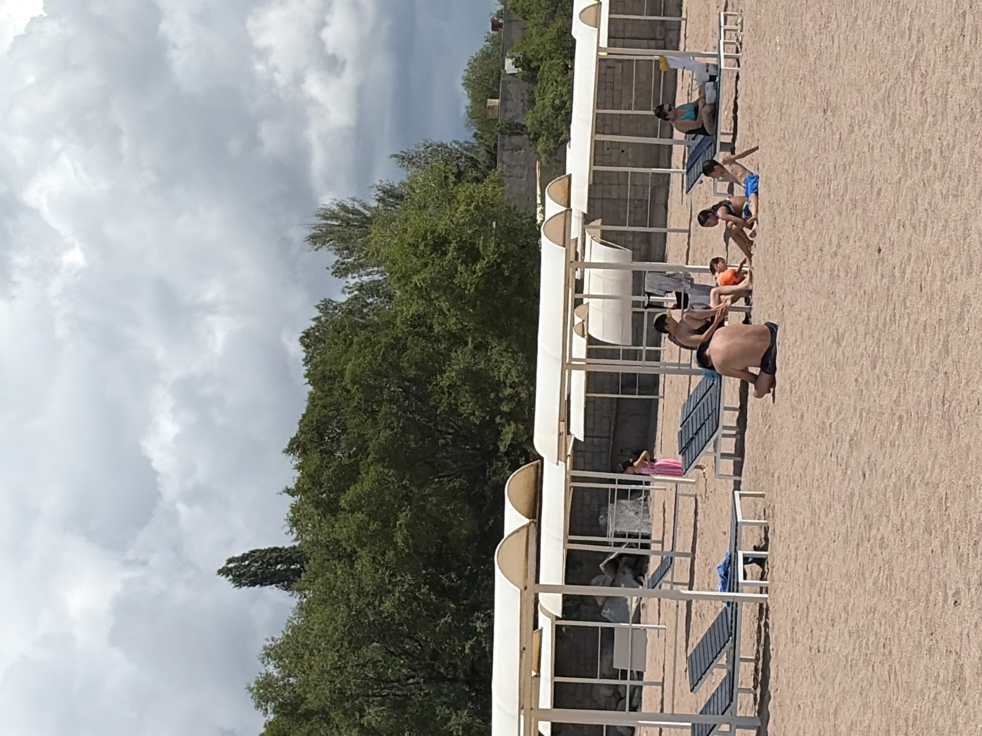 Relaxed beach day at a pier with calm water and canopies