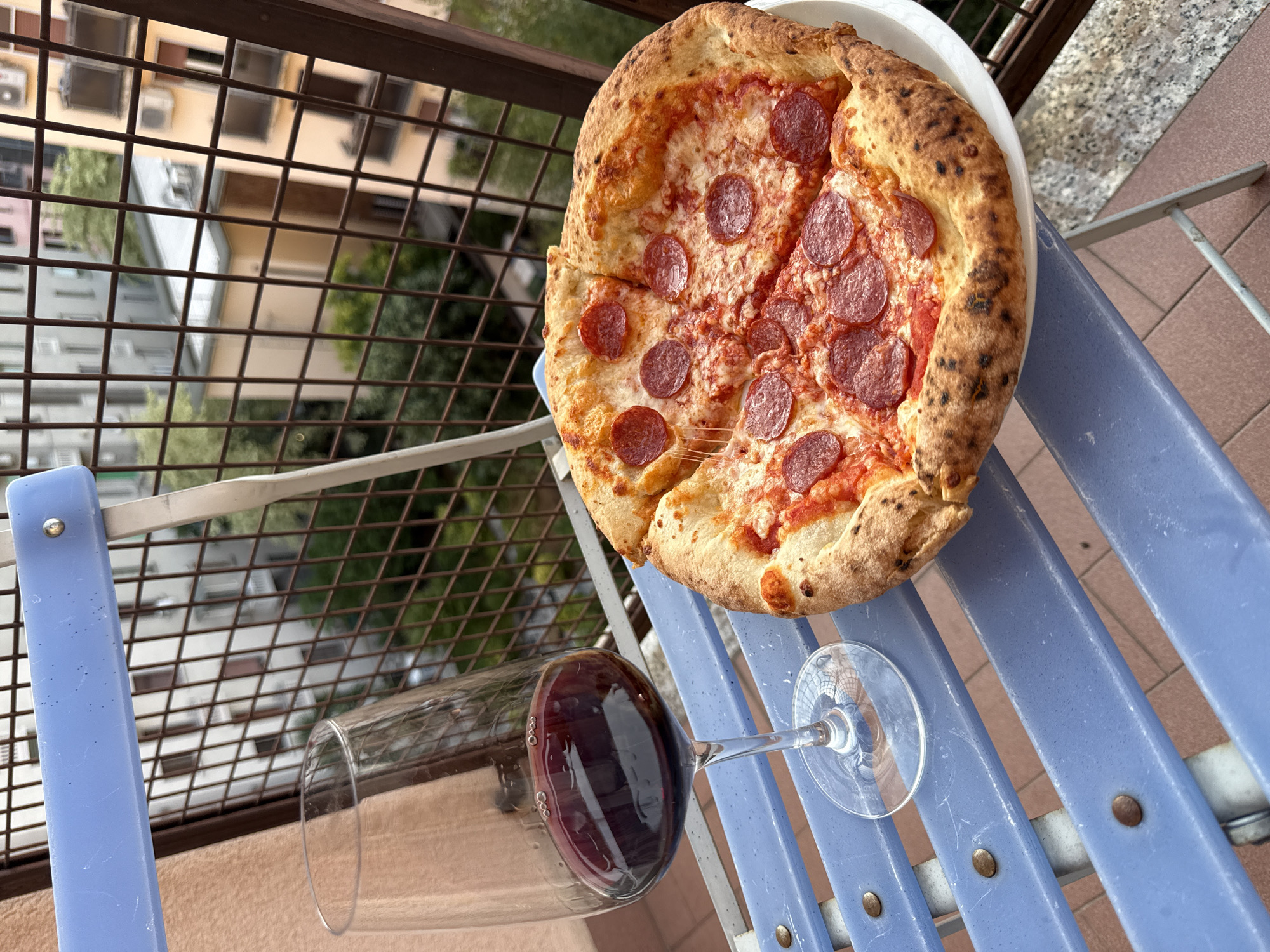 Red wine and pizza on a Milan balcony chair