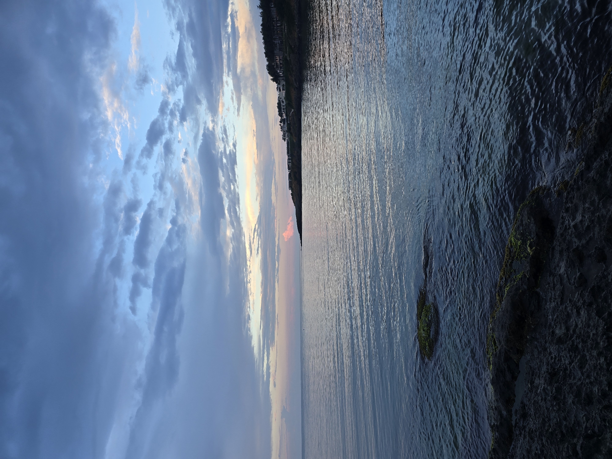 Rocky coastline at dusk, sunset colors and calm seas