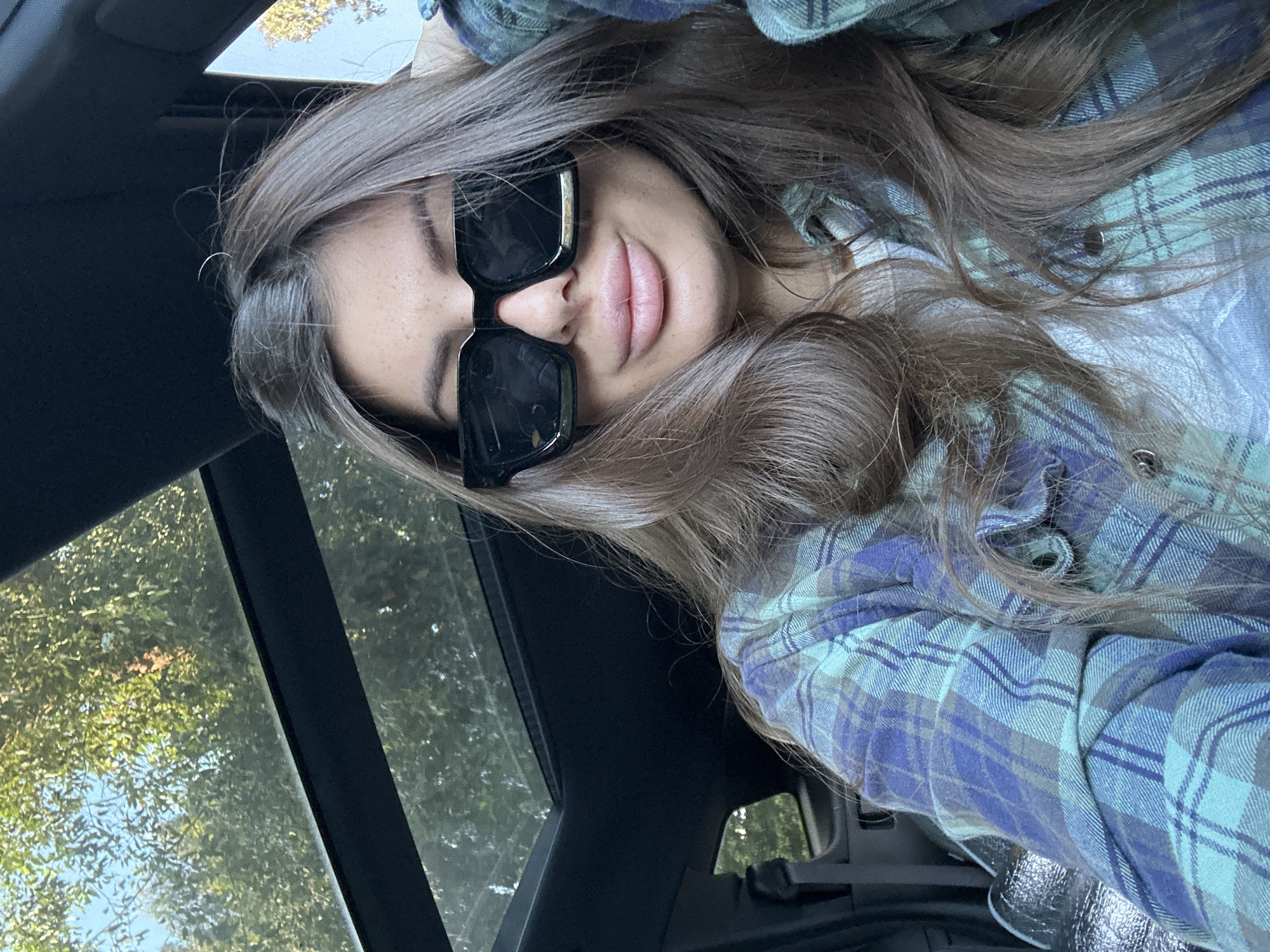 Woman in sunglasses rests in car, gazes at sunroof
