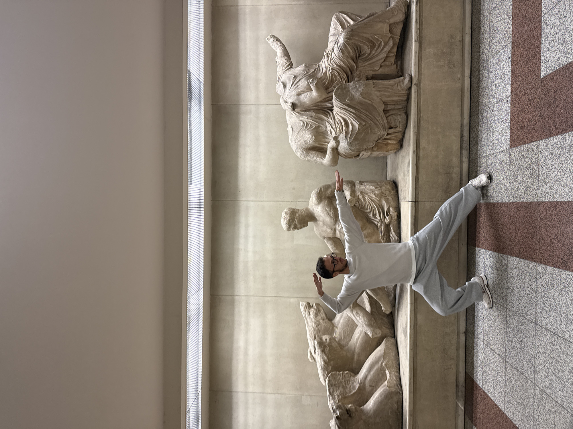 Tourist leaps near ancient sculptures at Athens Acropolis Museum