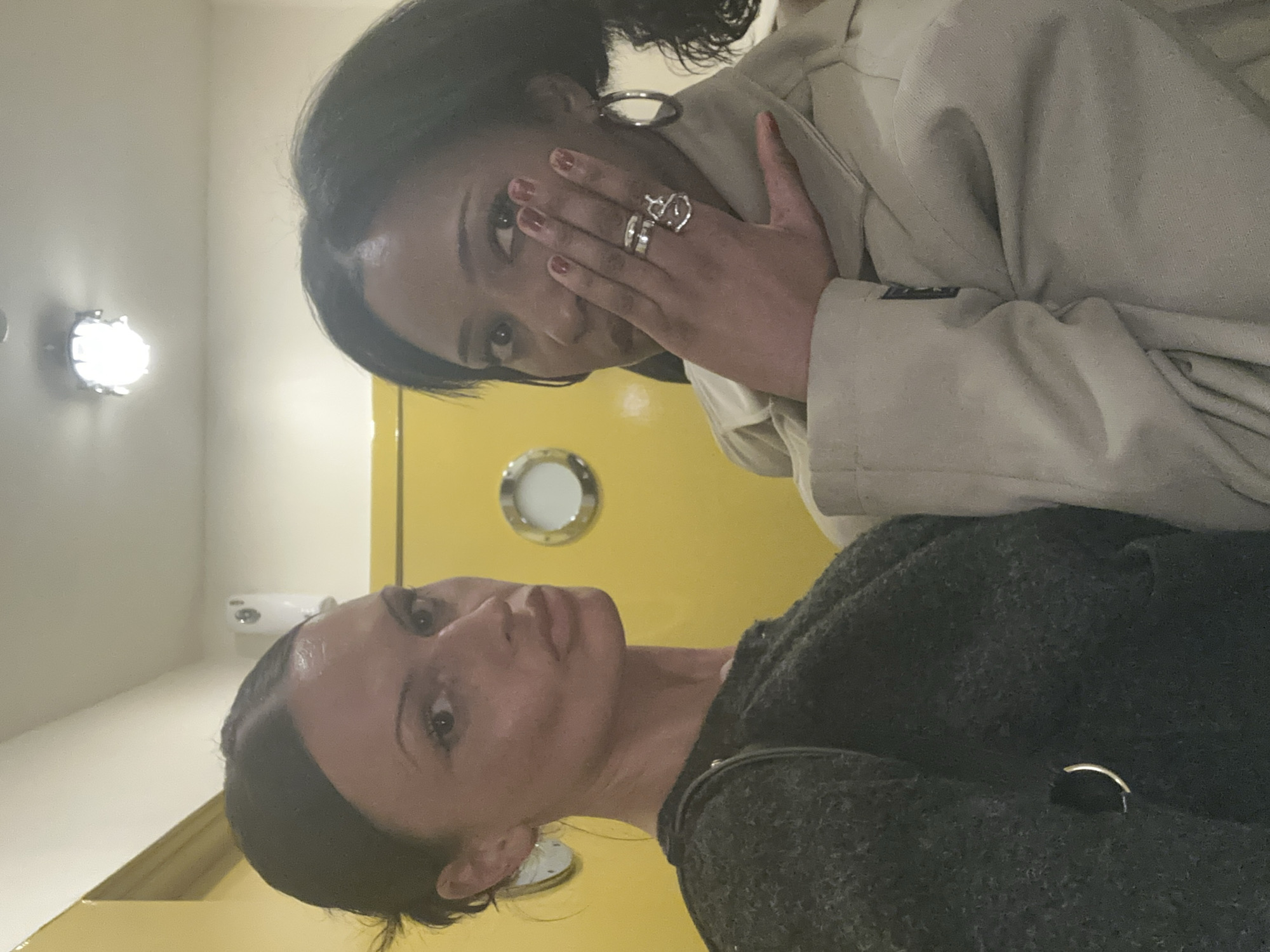 Two women photographed against yellow wall in London