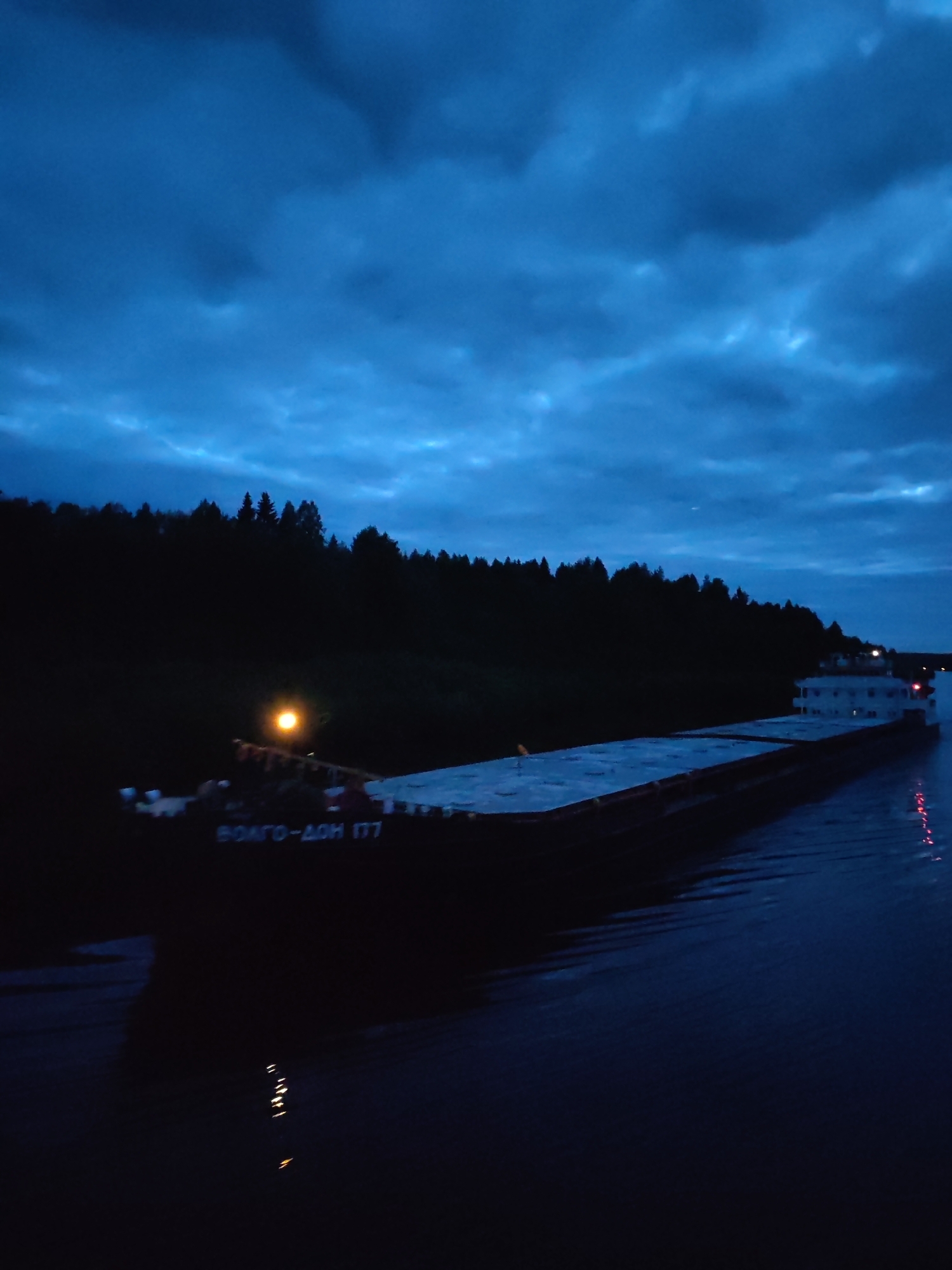 Cargo barge navigates Russian waterway near Старое Петровское at night