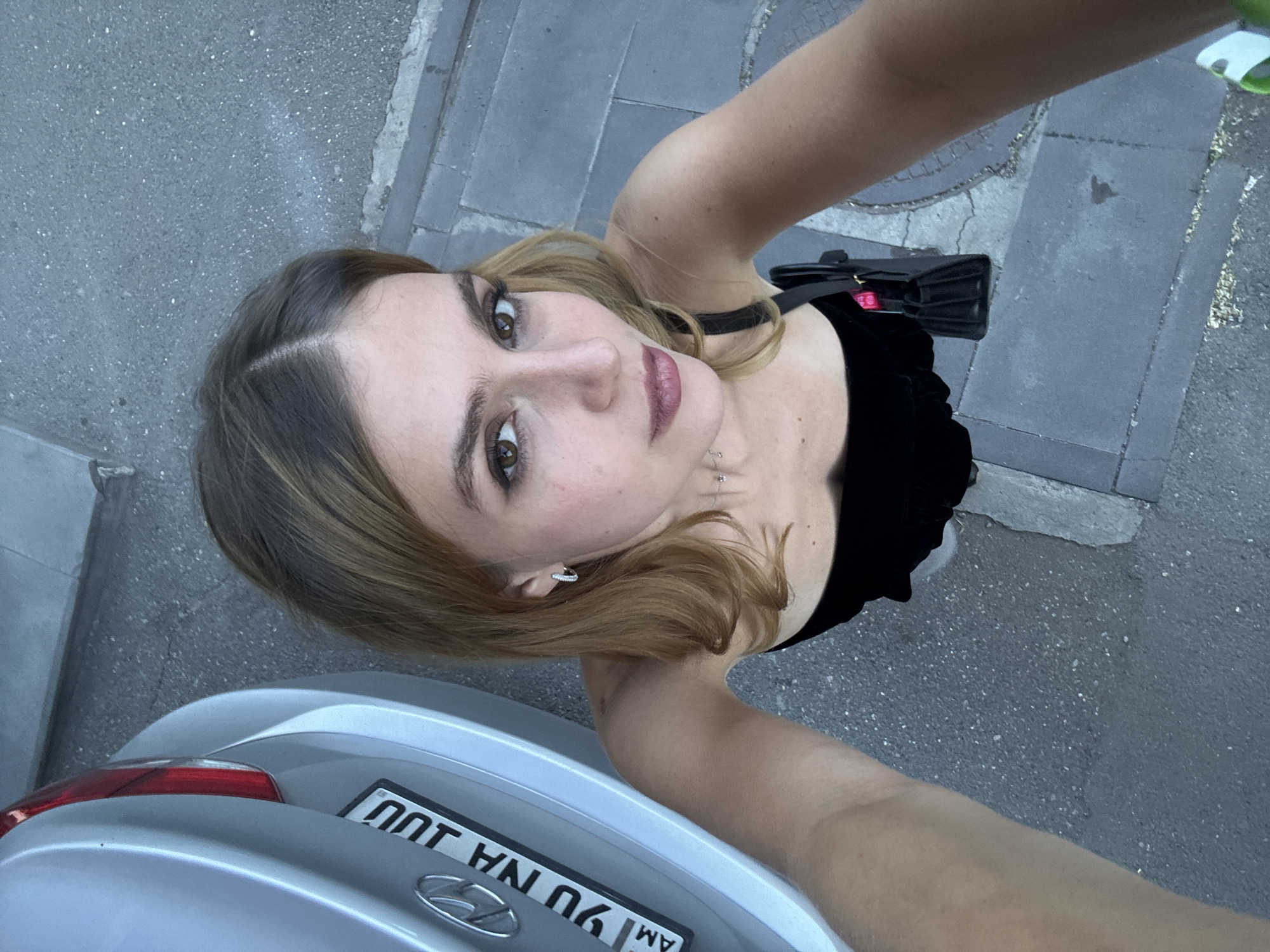 Woman takes selfie near silver car in Yerevan