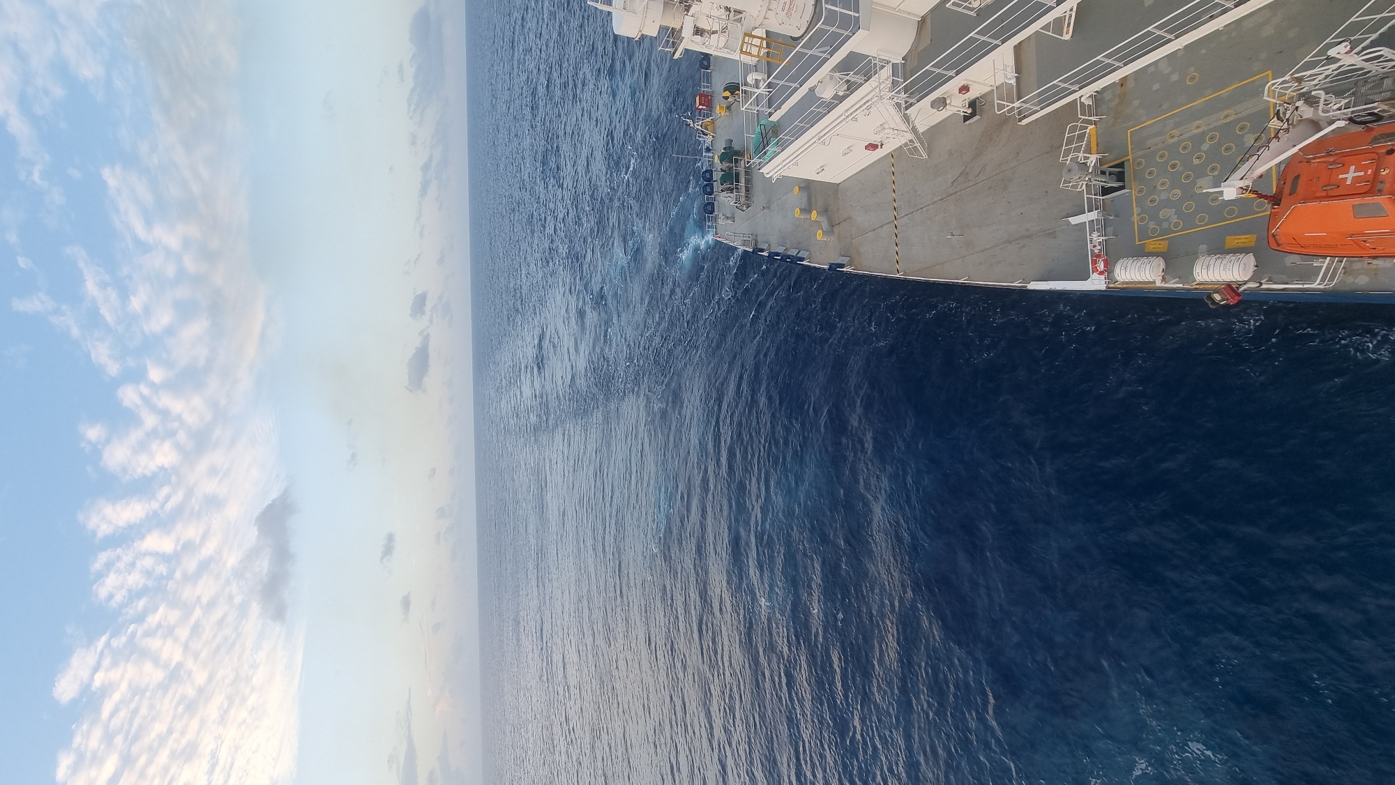 Ship cuts through deep blue Arabian Sea, wake trailing behind