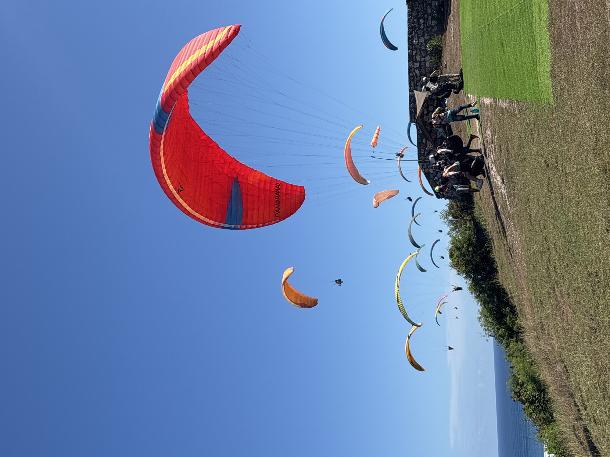 Colorful paragliders soar above Kuta Selatan coastline during morning session