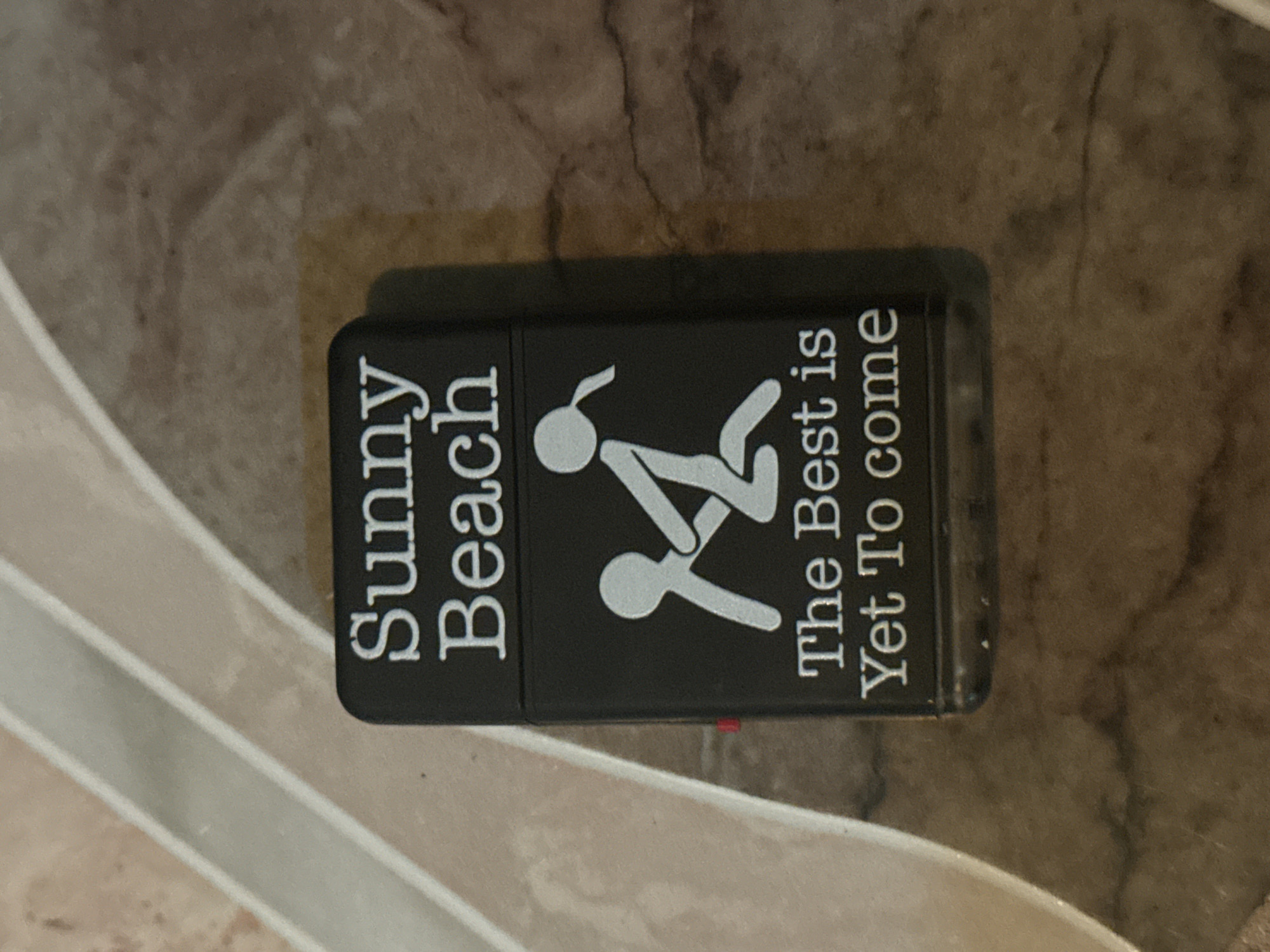 Sunny Beach branded Zippo lighter observed on marbled surface