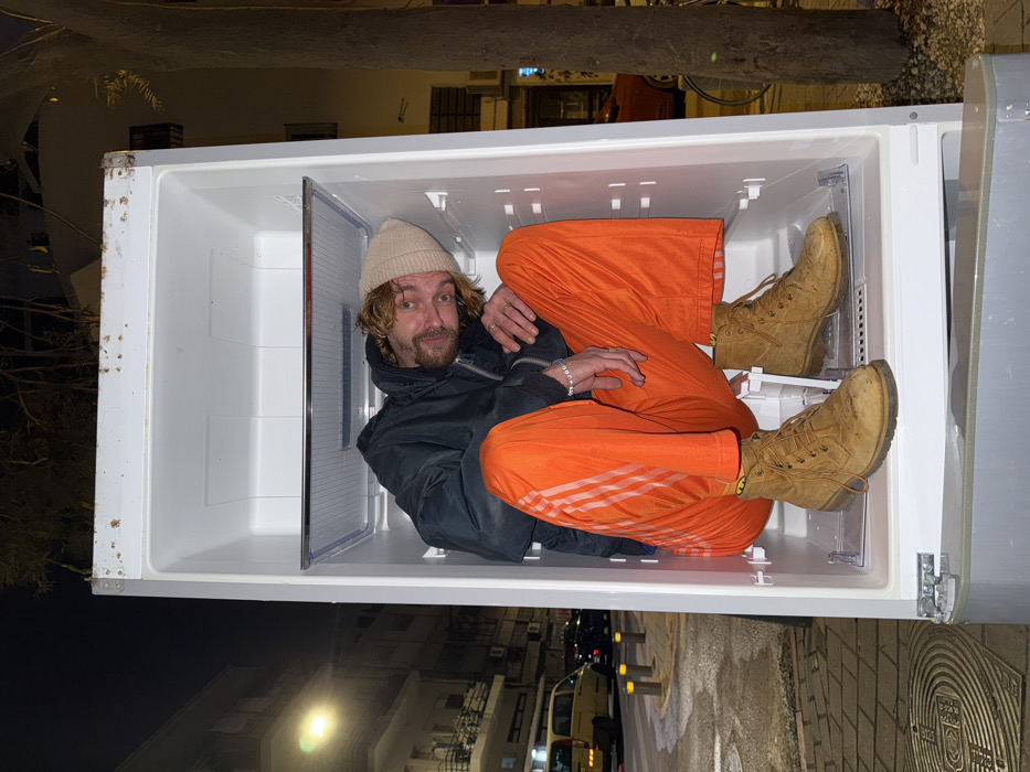 Person sits in outdoor refrigerator on Tel Aviv street